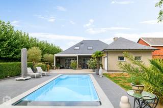 Op een centraal gelegen locatie te Onze-Lieve-Vrouw-Waver bevindt zich deze instapklare en hoogwaardig afgewerkte villa met zwembad, gelegen op een royaal perceel van 2.649 m² met een prachtig, vrij uitzicht over de achterliggende velden. Dankzij de gunstige ligging geniet u van een uitstekende bereikbaarheid, terwijl winkels, scholen, gezellige horecagelegenheden en het openbaar vervoer zich op wandelafstand bevinden.<br /><br />We betreden de woning via de inkomhal met vestiaire en een apart gastentoilet. De lichtrijke leefruimte biedt ruimschoots plaats voor het inrichten van een gezellige zithoek en een elegante eetruimte. Aangrenzend bevindt zich de keuken, uitgerust met kwaliteitstoestellen. Verder vinden we op deze verdieping nog twee volwaardige slaapkamers, een praktische bureauruimte, een eerste badkamer voorzien van een inloopdouche, ligbad en dubbel lavabomeubel, een apart toilet, een wasruimte en een inpandige garage.<br /><br />Op de eerste verdieping bevinden zich via de nachthal nog eens drie volwaardige slaapkamers en een tweede badkamer met inloopdouche, toilet en lavabo, evenals twee handige bergruimten. Aan parkeergelegenheid is er geen gebrek, met zowel ruim voldoende staanplaatsen als een royale carport. In de prachtig aangelegde tuin met terras kunt u steeds in alle rust en privacy genieten van het mooie weer, in het bijzonder onder het overdekte terras dat naadloos overgaat in het luxueuze zwembad. De woning is bovendien toekomstgericht uitgerust met zonnepanelen.<br /><br />Dit is een uitstekende opportuniteit indien u op zoek bent naar een instapklare woning met 5 slaapkamers, een zwembad en een prachtige tuin op een perceel van 2.649 m² te Onze-Lieve-Vrouw-Waver. Contacteer ons via 0472 22 12 41 of neem een kijkje op www.boonstravastgoed.be.<br /><br />Bijzonderheden:<br />- Zonnepanelen<br />- 5 slaapkamers<br />- Perceel = 2649 m²<br />- Luxueus zwembad