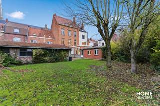 Aan de voet van de vestingen, in de schaduw van de Sint-Jacobskerk en pal in het hart van Ieper, bevindt zich deze karaktervolle herenwoning met uitzonderlijk grote tuin en bijgebouw. U betreedt het pand via de imposante toegangspoort, ooit doorgang voor koetsen, die vandaag kan uitgroeien tot een majestueuze inkomhal met directe toegang tot zowel de woning als de tuin. Op het gelijkvloers bevinden zich onder meer een voorkamer, traphal, woonkamer, aparte keuken, badkamer en slaapkamer. Daarboven wachten nog drie verdiepingen om volledig naar eigen smaak te worden ingericht. Met wat renovatiewerk en visie maakt u van dit pand één van de meest opvallende herenwoningen van Ieper – een unieke kans voor wie ruimte, authenticiteit en een topligging in het centrum zoekt.