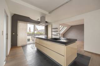 <p>Midden in het historische hart van Antwerpen, boven de daken van de Steenhouwersvest, bevindt zich dit uitzonderlijke penthouse met terras en een adembenemend zicht op de Onze-Lieve-Vrouwekathedraal. Met een bewoonbare oppervlakte van 184 m² combineert deze unieke eigendom licht, comfort en rust op een absolute toplocatie in de stad.</p>
<p>Bij het betreden van het appartement valt meteen de aangename openheid en overvloedige lichtinval op. De royale leefruimte met grote raampartijen geniet van een prachtig panoramisch zicht over de stad en de kathedraal. Hier woont u letterlijk boven het bruisende stadsleven, terwijl u tegelijk geniet van een zeldzame sereniteit en privacy.</p>
<p>De open leefruimte met volledig geïntegreerde keuken sluit naadloos aan op het terras, waardoor binnen- en buitenleven harmonieus in elkaar overvloeien. Daarnaast is er een extra keuken/bijkeuken voorzien die zorgt voor bijkomende opbergruimte en praktisch comfort.</p>
<p>De hoogwaardige afwerking met warm parket en natuursteen verleent het interieur een tijdloze en elegante uitstraling. Verder beschikt het penthouse over drie volwaardige slaapkamers, elk badend in natuurlijk licht. De badkamer werd stijlvol en functioneel ingericht met een dubbele wastafel, inloopdouche en toilet.</p>
<p>Een aparte dressing biedt extra comfort, terwijl de centrale trap naar de sfeervolle mezzanine het appartement een uniek karakter geeft. Tot slot beschikt de woning ook over een handige kelderberging.</p>
<p>De ligging maakt deze eigendom extra aantrekkelijk: gezellige restaurants, winkels, musea en terrasjes bevinden zich op wandelafstand. Bovendien bestaat de mogelijkheid om een parkeerplaats aan te kopen voor € 65.000.</p>
<p>Gebouwd in 1992 vormt dit penthouse een geslaagde combinatie van stijl, comfort en een uitzonderlijke ligging.</p>
<p>Een unieke woonkans voor wie op zoek is naar een karaktervolle penthouse met één van de mooiste uitzichten die Antwerpen te bieden heeft.</p>