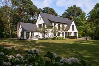 Deze karaktervolle villa is achterin gelegen op een ruim perceel van 5.765 m² op een toplocatie vlak bij het centrum van Heide-Kalmthout.<br />De villa werd doorheen de jaren netjes gerenoveerd en is als volgt ingedeeld: Ruime inkomhal op tegelvloer met gastentoilet met handenwasser en vestiairekast. Naast de inkomhal bevindt zich een aparte kantoorruimte op parket met gashaard. Verder door betreden we de open en ruime leefruimte op parket. De leefruimte bestaat uit een gezellige zithoek met gashaard. Aansluitend bevindt zich de open leefkeuken. Hiernaast bevindt zich nog een gezellige open en lichte eetkamer, met haard, en omgeven door ramen en zicht op de tuin. Aansluitend is er nog een gezellig en zonnig terras. Tenslotte bevindt er zich op het gelijkvloers nog een praktische wasplaats met veel opbergkasten en een laatste polyvalente ruimte met water aansluiting. Ideaal als hobbyruimte of speelkamer. Via de royale trap in de inkomhal toegang tot de eerste verdieping die als volgt is ingedeeld: Ruime en lichte overloop. Eerste zeer ruime kamer op parket met zicht op het achtergelegen natuurdomein. Tweede kamer op parket met zicht op de tuin. Derde kamer op parket met zicht op de tuin. Badkamer met douche, dubbele wastafel en wc. Ingemaakte vestiarekasten op de overloop. Ruime hoofdslaapkamer op parket met ensuite badkamer met ligbad, douche, dubbele wastafel en wc. (vernieuwd) Hiernaast bevindt zich ook nog een praktische inloopdressing en tenslotte nog een 5e ruimte waar momenteel een sauna is ondergebracht.<br />Bergzolder bereikbaar via vlizotrap.<br />Het perceel beschikt over een zeer mooie tuin en lange oprijlaan. Voldoende parkeergelegenheid voor de woning, alsook een dubbele garage achteraan, met automatische poort.<br />Het perceel wordt gekenmerkt door een groen en rustig karakter, met een mooi bomenbestand en variërende aanplantingen. Bovendien is er via een poortje achteraan, rechtstreeks toegang tot het natuurdomein: De Withoefse Heide.<br />Dak vernieuwd in 2020.