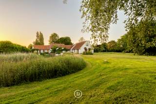 Deze karaktervolle hoeve bevindt zich in een discrete, landelijke omgeving en wordt aangeboden op een uitzonderlijk ruim perceel van in totaal 21.760 m². De combinatie van ruimte, groen en prachtige vergezichten over de omliggende weilanden zorgt voor een bijzonder aangename en rustige woonomgeving.<br /><br />De zuidgerichte tuin sluit mooi aan op de woning en beschikt over een terras en vijver. Daarnaast is er een ruime garage met plaats voor meerdere wagens, een werkruimte en voldoende opslagmogelijkheden voor tuinmateriaal.<br /><br />Binnenin is de woning praktisch en ruim opgevat. De lichtrijke woonkamer met hoog plafond vormt het hart van de woning en geniet, net als verschillende andere ruimtes, van een mooi contact met de groene omgeving. Verder beschikt de eigendom over een volledig uitgeruste keuken, zes slaapkamers en drie badkamers.<br /><br />Met een totale grondoppervlakte van 21.760 m² is dit een interessante eigendom voor wie op zoek is naar een karaktervolle hoeve met veel ruimte, privacy en een uitgesproken landelijk karakter.