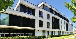 De ligging van Dans tussen het Jan Frans Willemsplein en de Boelare, is op z’n minst bijzonder te noemen. Dans maakt de verbinding tussen het park De Fonteyne en de nog te realiseren zorgcampus Dr. Coppens. Het resultaat? Een oase van rust, midden in de stad, waar het heerlijk wonen is en ieder appartement uitkijkt op groen. Véél groen, want heel de site wordt bovendien omsloten door een aangelegde parkomgeving dat voor u wordt onderhouden. Ideaal om tot rust te komen na een drukke werkdag of gewoon te genieten van de natuur.
Op korte wandelafstand van Dans ligt de markt van Eeklo met tal van faciliteiten en winkels. Handig voor wie snel nog even om boodschappen moet of beter nog, met vrienden ’s avonds wil genieten van een zomers terras.
De indeling is als volgt: een grote inkomhal met inbraakwerend deur en toegang tot de open, lichtrijke leefruimte en open keuken, apart toilet, 3 slaapkamers, een badkamer met badkamermeubel met dubbele lavabo en grote inloopdouche, berging met aansluitingen voor wasmachine en droogkast en en een zonnig, overdekt terras waar u volop kunt genieten.
Het appartement heeft een kelderberging, een ondergrondse autostandplaats en een gemeenschappelijke fietsenberging.
Wenst u een bezoek te brengen om dit prachtige appartement te ontdekken? Boek online uw afspraak via www.vastgoedunicum.be of stuur een e-mail naar verhuur@vastgoeduniucm.be.