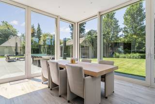Deze prachtige, ruime villa is gelegen op een mooi aangelegd perceel met een uitzonderlijk gevoel van rust en privacy. De woning combineert royale leefruimten met een praktische indeling en tal van extra's, waaronder een buitenzwembad, een sfeervolle buitenkeuken met bar, een cinemaruimte en een indrukwekkende vrijstaande garage met plaats voor vier wagens. De fraai aangelegde tuin vormt een oase van groen.<br /><br />De woning omvat op het gelijkvloers een inkomhal, een ruime leefruimte bestaande uit een zithoek met houtkachel, eetkamer en gezellige tv-/leeshoek, een veranda met uitzicht op de tuin, een volledig ingerichte keuken, een bijkeuken/wasplaats, een ingerichte badkamer met dressing, een multifunctionele bar met buitenkeuken en verdieping met opslagruimte en cinemazaal, een dubbele inpandige garage en een kelder.<br /><br />Op de eerste verdieping bevinden zich vier volwaardige slaapkamers, een ingerichte douchekamer en een praktische bergzolder, bereikbaar via vast trap (met valluik).<br /><br />De prachtige tuin is voorzien van een buitenzwembad met een ruim overdekt terras en een voorziening voor een berging of kleedruimte. Daarnaast beschikt het eigendom over een vrijstaande garage met plaats voor vier wagens en een tuinhuis.<br /><br />Een uniek geheel met tal van mogelijkheden, afgewerkt met oog voor comfort en gelegen in een bijzonder groene en private omgeving.<br /><br />Indeling<br />Gelijkvloers<br />Via de inkomhal met gastentoilet en vestiaire en trap naar de eerste verdieping betreedt u deze ruime woning. De royale leefruimte is speels ingedeeld dankzij enkele niveauverschillen, waardoor een aangename en karaktervolle sfeer ontstaat. De zithoek met houtkachel vormt het gezellige hart van de woning en sluit mooi aan op de eetkamer en de afzonderlijke tv-/leeshoek.<br /><br />Aansluitend bevindt zich de lichtrijke veranda, waar u het hele jaar door kunt genieten van een prachtig uitzicht over de fraai aangelegde tuin.<br /><br />De volledig ingerichte keuken (combi-oven, heteluchtoven, koelkast, vaatwasser, inductiekookplaat, dampkap en grillplaat) biedt alle nodige comfort. Via de achteringang komt u in een sas dewelke toegang biedt tot de praktische bijkeuken/wasplaats, de ingerichte badkamer met aansluitend dressing en de keuken.<br /><br />Een absolute meerwaarde is de gezellige bar met buitenkeuken. Via een vaste trap bereikt u de verdieping boven deze ruimte, waar zich een praktische opslagruimte en een sfeervolle cinemazaal bevinden.<br /><br />Verder beschikt het gelijkvloers over een dubbele inpandige garage en een kelder die extra bergruimte biedt.<br /><br />Eerste verdieping<br />Via de trap in de inkomhal bereikt u de overloop, die toegang verleent tot vier ruime slaapkamers en een douchekamer (wastafel, douche en toilet).<br /><br />Via een vaste trap (met valluik) bereikt u bovendien de praktische opbergzolder.<br /><br />Kelder<br />De woning beschikt over een praktische kelder die dienst doet als extra opslagruimte.<br /><br />Tuin<br />De prachtig aangelegde tuin biedt optimale privacy en vormt een heerlijke plek om tot rust te komen. Het buitenzwembad vormt samen met het ruime overdekte terras het perfecte decor om te genieten van warme zomerdagen. Bij het zwembad zijn tevens voorzieningen aanwezig voor een berging en/of kleedruimte.<br /><br />Verder bevindt zich achteraan het perceel een ruime vrijstaande garage met plaats voor vier wagens. Daarnaast is er nog een afzonderlijk tuinhuis aanwezig.<br /><br />Bijzonderheden<br />•Zeer ruime villa met speelse indeling <br />•Hoogwaardige afwerking<br />•Alarm<br />•Camerabewaking (5 camera’s aanwezig)<br />•Volledig omheind en afgesloten perceel<br />•Airco aanwezig (veranda en hoofdslaapkamer)<br />•Buitenzwembad (4,5 x 11m)<br />•Vrijstaande garage van ca. 90 m²<br />•Verwarming op aardgas<br />•Zuidwest georiënteerde tuin