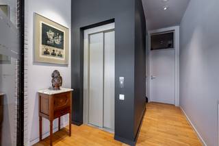 <p>Deze<strong> uitzonderlijke wonin</strong>g met een bewoonbare oppervlakte van 440m² werd ontworpen rond een centraal volume waarin de lift is ondergebracht. Dankzij deze doordachte indeling geniet de woning van een logische circulatie, veel lichtinval en een bijzonder ruimtelijk gevoel. Bovendien biedt de combinatie van een volwaardige privéwoning met een volledig geïntegreerde kantoorruimte tal van mogelijkheden voor vrije beroepen, zelfstandigen of gezinnen die wonen en werken willen combineren of om in te richten als een <strong>kangoeroewoning. </strong><br />Het gelijkvloers is functioneel ingedeeld. De kantoorruimte beschikt over een eigen inkom, aangevuld met een archiefruimte, terwijl ook de privéwoning een afzonderlijke toegang heeft.<br />Daarnaast bevindt zich op deze verdieping een extra casco leefruimte die perfect kan worden ingericht als tv-kamer, hobbyruimte, praktijkruimte of als uitbreiding van het kantoor. Dankzij de kamerhoge raampartijen geniet deze ruimte van een prachtig zicht op de zonnige tuin en een aangename natuurlijke lichtinval.<br />De garage biedt niet alleen plaats aan minstens 2 wagens, maar geeft tevens rechtstreeks toegang tot de tuin. Deze buitenruimte kan desgewenst ook als bijkomende parkeergelegenheid worden ingericht.<br /><strong>Eerste verdieping</strong><br />Via de centrale hal met vestiaire en gastentoilet bereikt u de leefverdieping.<br />Aan de achterzijde bevindt zich de royale leefruimte, die uitgeeft op een ruim, zuidgericht terras waar u de hele dag van de zon kunt genieten. Aan de voorzijde bevindt zich een extra salon, leeskamer of speelkamer, die aansluit op de ruime leefkeuken. Vanuit de keuken heeft u toegang tot een gezellig balkon.<br /><strong>Tweede verdieping</strong><br />De slaapverdieping omvat een comfortabele master bedroom met een ensuite badkamer. Daarnaast bevinden zich nog drie bijkomende slaapkamers.<br />Twee slaapkamers worden gescheiden door een badkamer met douche en lavabo. Eén van deze kamers beschikt bovendien over een eigen balkon. Verder is er nog een logeerkamer met balkon, een apart toilet en een praktische wasruimte.<br /><strong>Zolderverdieping</strong><br />De volledig geïsoleerde zolderverdieping biedt nog heel wat extra mogelijkheden en beschikt bovendien over een sfeervolle patio, die zorgt voor extra licht en een aangename buitenbeleving.<br />De woning is volledig onderkelderd en biedt hierdoor een overvloed aan bergruimte en praktische mogelijkheden.<br />Deze exclusieve woning combineert tijdloze architectuur, uitzonderlijke volumes en een uiterst flexibele indeling. Een ideale eigendom voor wie op zoek is naar een prestigieuze gezinswoning met geïntegreerde kantoor- of praktijkruimte, zonder in te boeten aan comfort, privacy of woonkwaliteit.</p>