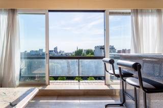 Aan de vernieuwde Leien, vlak bij de iconische Paardenmarkt, bevindt dit appartement zich temidden van alles wat de stad zo levendig maakt. De bruisende mix van het Eilandje, het historische stadscentrum, Park Spoor Noord en de levendige Stadswaag ligt allemaal binnen handbereik. Dankzij de goede bereikbaarheid en de nabijheid van het openbaar vervoer (tram, bus, trein) ben je moeiteloos verbonden met elke uithoek van de stad én daarbuiten. Het appartement is gelegen op achtste verdieping (lift gaat tot de zevende verdieping en de achtste verdieping is dan te bereiken via de trap) en biedt een prachtig zicht over de Antwerpse skyline. Grote raampartijen zorgen voor een overvloed aan zon- en daglicht, wat bijdraagt aan een heerlijk open gevoel. Het appartement werd steeds met zorg onderhouden, maar biedt tegelijk nog ruimte om het geheel naar eigen smaak op te frissen en te personaliseren. De leefruimte biedt meer dan voldoende plaats om een grote zithoek en eetkamer te installeren. Aansluitend vindt u een open keuken die volledig en gebruiksvriendelijk is geïnstalleerd. Aan de achterzijde van het appartement bevinden zich twee volwaardige slaapkamers, waarvan één toegang geeft tot een charmant terras. Daarnaast is er nog een derde kamer, perfect in te richten als bureau, hobbyruimte of logeerkamer. De badkamer bestaat uit een douche, wastafel en een tweede toilet. Epc: 322 kWh/m2, P-score: A, G-score: A, Vg-Wche-Gvkr-Gvv-Gmo.