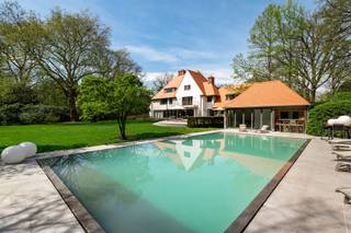 <p><span> </span></p><p><span>Deze ruime en kwalitatief afgewerkte villa is gelegen op een rustig en groen perceel en geeft comfort, privacy en snelle toegang naar alle snelwegen. De woning werd praktisch ingedeeld en biedt tal van mogelijkheden voor wonen, werken en ontspannen, zowel binnen als buiten. </span></p><p><span> </span></p><p><span>U betreedt de woning via de inkomhal met gastentoilet en directe toegang tot de bureauruimte/bibliotheek. Dit bureel is dus ideaal gelegen om mensen te ontvangen zonder dat men in de rest van de woning moet komen.  </span></p><p><span>De woonkamer is zeer ruim en vormt het centrale gedeelte van de woning. Deze leefruimte biedt een prachtig panoramisch zicht over de tuin. De living werd ingedeeld met een ruime zithoek bij de open haard en formele eetplaats. Aansluitend bevindt zich de leefkeuken met ontbijtzone,  welke praktisch werd ingericht en rechtstreeks verbonden is met de leefruimtes. Achter de keuken bevindt zich nog een tweede gastentoilet evenals een aparte audio- of homecinemaruimte, met daarboven een nog aparte studio. </span></p><p><span> </span></p><p><span>1e Verdieping</span></p><p><span>Via de centraal gelegen trap bereikt u de nachthal op de eerste verdieping. Hier bevindt zich een eerste ruime slaapkamer met aansluitende badkamer die gedeeld wordt met een achterliggende tweede slaapkamer. Verder is daarnaast een praktische wasplaats op deze verdieping. </span></p><p><span>De grote mastersuite beschikt over een ruime slaapkamer met aansluitende dressing (voorheen nog extra slaapkamer) en een royale badkamer voorzien van sauna en een ruime inloopdouche. Aan de voorzijde van de woning bevindt zich een studeerkamer welke ook deel uitmaakt van de mastersuite en welke eveneens dienst kan doen als een tweede dressing. Deze avond study is voorzien van een open haard.</span></p><p><span> </span></p><p><span>2e Verdieping</span></p><p><span>Ook de tweede verdieping werd volledig benut. Hier bevindt zich een bergzolder met ingemaakte kasten welke ideaal dienst doet als opbergruimte. Ook werd op de tweede verdieping een extra suite ingericht met aansluitende badkamer evenals een aparte studeer- of bibliotheekruimte. Daarnaast bevindt zich op deze verdieping nog een slaapkamer. </span></p><p><span> </span></p><p><span>Kelder</span></p><p><span>De woning is volledig onderkelderd. Hier bevinden zich diverse technische ruimtes en praktische bergruimtes. Tevens zijn er twee royale geklimatiseerde wijnkelders aanwezig. </span></p><p><span> </span></p><p><span>Garages en parkeren</span></p><p><span>Vooraan het perceel bevindt zich een ruime parkeerplaats met plaats voor circa 13 wagens evenals een carport naast de woning voor twee frequent gebruikte voertuigen, vlakbij de woning. </span></p><p><span>Achteraan het perceel, langs de oprit die aan de rand van het domein loopt, bevindt zich een afzonderlijke garage met plaats voor negen autos. </span></p><p><span> </span></p><p><span>Tuin en buitenruimtes</span></p><p><span>De tuin biedt u volledige privacy. Er is een ideaal gelegen zwembad dat recent gerenoveerd werd met ruime terrassen en aansluitend een poolhouse met leefruimte, douche, toilet en sauna. </span></p><p><span>Achteraan op het perceel bevindt zich een charmante chalet met twee slaapkamers, een keuken en een woonkamer, ideaal als gastenverblijf. </span></p><p><span> </span></p><p><span>Bijzonderheden</span></p><p><span>Deze exclusieve villa combineert royale woonruimtes met veel mogelijkheden tot ontspanning zoals zwembad, wellness en homecinema. De villa is zowel geschikt voor een groot gezin als voor een combinatie van wonen en werken. Dankzij onder meer de ruime parkeermogelijkheden, de volledig onderkelderde woning en het bijkomende gastenverblijf biedt dit eigendom een uitzonderlijk wooncomfort in een groene omgeving nabij het centrum van Brasschaat. </span></p><p><span> </span></p><p><span>Meer inlichtingen via ons kantoor.</span></p>