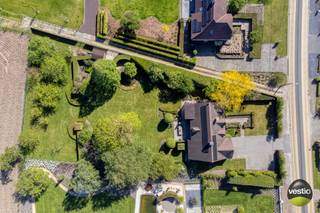 We vinden deze charmante villa met een karaktervolle uitstraling op een ruim perceel van 35a10ca, gelegen aan Russelt 106 in Wellen. De woning bevindt zich langs een vlotte verbindingsweg tussen het centrum van Alken en Wellen, met een snelle aansluiting op de expresweg richting Hasselt en Sint-Truiden. Openbaar vervoer, winkels, scholen en andere voorzieningen liggen in de directe omgeving.<br /><br />De villa werd gebouwd in 2000 met duurzame en kwalitatieve materialen en onderging in 2018 een grondige renovatie. Hierbij werden onder andere een nieuwe keuken en badkamer geplaatst, een bureauruimte op maat ingericht en de tuin volledig opgefrist. Daarnaast werden er twee poorten voorzien langs de servitudeweg en werd het perceel volledig omheind. In 2024 werd de woning verder geoptimaliseerd met de installatie van zonnepanelen (totaal vermogen 8.700 Wp) en een laadpaal.<br /><br />Met een bewoonbare oppervlakte van circa 380 m² en een perceel van 35a10ca staan ruimte, rust en privacy hier centraal. Bovendien beschikt de woning over een energiezuinig EPC-label B met een waarde van 160 kWh/m².<br /><br />Bij het betreden van de woning komt u in een ruime inkomhal met vestiaire en gastentoilet, die toegang biedt tot een stijlvolle bureauruimte op maat. In het interieur werd gekozen voor hoogwaardige en tijdloze materialen zoals massieve eik, travertin (perlato) en natuursteen, wat bijdraagt aan de warme en luxueuze uitstraling van de woning.<br /><br />De lichtrijke leefruimte met zit- en eethoek sluit naadloos aan op de op maat gemaakte keuken. Deze keuken is afgewerkt met een werkblad in Zimbabwe Black natuursteen en uitgerust met kwalitatieve toestellen, waaronder een Falcon inductiefornuis met salamander, hetelucht- en combioven, dampkap Novy, vaatwasser AEG en koelkast AEG.<br /><br />Vanuit zowel de leefruimte als de keuken geniet u van een prachtig zicht op de aangelegde tuin met fruitbomen en achterliggende weilanden. Aansluitend aan de keuken bevinden zich nog een praktische wasplaats met ingebouwde kasten, een aparte douchecel, een koel- en fietsenberging en twee standplaatsen met sectionale poorten, evenals de technische ruimte.<br /><br />Op de eerste verdieping geeft de ruime overloop toegang tot de master bedroom met dressing en een luxueuze badkamer, voorzien van ligbad, een inloopdouche in natuursteen en keramische panelen, dubbele wastafel en toilet. Daarnaast zijn er nog vier ruime slaapkamers en een tweede badkamer met douche, wastafel en apart toilet. Beide badkamers zijn bovendien uitgerust met vloerverwarming.<br /><br />De volledig geïsoleerde zolder, bereikbaar via een luik, biedt extra opslagmogelijkheden.<br /><br />De zuidoost georiënteerde tuin is een absolute troef: met een breedte van ongeveer 40 meter en een volledige omheining geniet u hier van optimale privacy en een open zicht op de achterliggende boomgaard en weilanden. Het (deels overdekte) terras met zonneluifel, de buitenbarbecue, de gezellige zithoek aan de vijver en het tuinhuis maken het geheel compleet.<br /><br />Troeven van de woning:<br />+ Ruim perceel van 35a10ca met een breedte van ca. 40 meter - straatbreedte 30 meter<br />+ Bewoonbare oppervlakte van ca. 380 m² (volgens EPC) - plafondhoogte inkomhal 3,08 m - plafondhoogte living/keuken 2,62 m<br />+ Karaktervolle en tijdloze architectuur<br />+ Luxueuze afwerking met hoogwaardige materialen (massieve eik, travertin, natuursteen)<br />+ Volledig instapklaar dankzij renovatie<br />+ Zeer praktische woonindeling met veel licht<br />+ Energiezuinig (EPC-label B – 160 kWh/m²)<br />+ Zonnepanelen en laadpaal aanwezig<br />+ 5 volwaardige, ruime slaapkamers<br />+ Rustige, groene omgeving met open zicht<br />+ Volledige privacy in de tuin<br /><br />Kortom, deze landelijke villa combineert ruimte, comfort en hoogwaardige afwerking met een uitzonderlijk gevoel van rust en privacy — een ideale thuisbasis voor wie op zoek is naar stijlvol wonen.<br /><br />Wenst u meer informatie of een bezoek ter plaatse? Neem gerust contact op met Stephanie Odeurs via 0474 73 64 84 of via e-mail: stephanie@vestio.com.