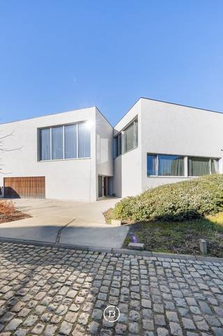In een strategisch gelegen en uitstekend bereikbare woonomgeving in Grimbergen bevindt zich deze stijlvolle, hedendaagse villa met zwembad, waar comfort, luxe en energiezuinigheid naadloos samenkomen. Dankzij de uitstekende EPC-score A, ondersteund door zonnepanelen, een warmtepomp, vloerverwarming en een geavanceerd ventilatiesysteem, geniet u hier van duurzaam en toekomstgericht wonen met een uitzonderlijke afwerkingsgraad.<br /><br />Bij het betreden van de woning wordt u verwelkomd in een elegante inkomhal met aansluitend een praktisch bureel, ideaal voor wie wonen en werken wil combineren. De lichtrijke leefruimte met grote raampartijen en een sfeervolle open haard vormt het warme hart van de woning.<br /><br />De open, hyperuitgeruste keuken is een echte eyecatcher en werd afgewerkt met hoogwaardige materialen. Het natuurstenen kookeiland, de maatwerkkasten, de inloopkoelkast en de ingebouwde toestellen maken van deze ruimte een perfecte combinatie van esthetiek en functionaliteit.<br /><br />De villa telt vier ruime slaapkamers. De kinderkamers delen samen één badkamer, terwijl ook de gastenkamer over privatief sanitair beschikt. De masterbedroom beschikt over een dressing, wasruimte en ensuite badkamer met ligbad en inloopdouche. Een hobbyruimte vervolledigt het geheel. Buiten geniet u van een aangelegd terras met zwembad. Een dubbele garage, bergingen, parkeerplaats op de oprit en domotica zorgen voor extra comfort en functionaliteit.<br /><br />Deze woning biedt een harmonieuze combinatie van ruimte, luxe en technologie op een gegeerde locatie in Grimbergen.