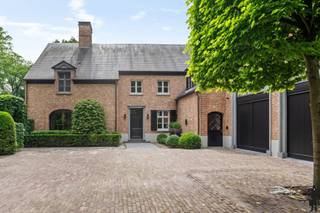 <p><strong>Luxueuze villa</strong> (ca. 700 m² bewoonbaar) die <strong>stijlvolle architectuur</strong> combineert met hedendaags wooncomfort. Gelegen in een <strong>residentiële laan nabij het centrum van Kapellen</strong>, op een dubbel perceel met een straatbreedte van 54 meter, biedt dit eigendom <strong>ruimte, privacy en pure elegantie</strong>.</p>
<h3>Gelijkvloerse verdieping</h3>
<p>– Representatieve inkomhal met vestiaire, gastentoilet en traphal<br />– <strong>Riante woonkamer</strong> met verschillende zithoeken, bibliotheek en open zicht op de tuin<br />– Aansluitende eetkamer met doorgang naar de tuin<br />– <strong>Leefkeuken op maat</strong> met kookeiland en hoogwaardige inbouwtoestellen<br />– Bureau of extra zithoek aan de voorzijde<br />– Inpandige garage voor twee wagens, bijkomende garage in vrijstaand bijgebouw<br />– Praktische dienstgangen en wasruimte</p>
<h3>Eerste verdieping</h3>
<p>– Bereikbaar via 2 trappen of <strong>lift</strong><br />– <strong>Mastersuite</strong> met slaapkamer, dressing en <strong>designbadkamer</strong> met inloopdouche, dubbele lavabo en infrarood sauna<br />– Tweede en derde slaapkamer met gedeelde badkamer<br />– Vierde slaapkamer met privatief balkon<br />– Vijfde slaapkamer met eigen badkamer en dressing<br />– Polyvalente ruimte boven de garage (kantoor, speel- of hobbykamer)</p>
<h3>Tweede verdieping</h3>
<p>– Volledig afgewerkt als <strong>multimediaruimte, hobbyruimte of extra slaapkamers</strong></p>
<h3>Kelder</h3>
<p>– Wijnkelder<br />– Technische ruimte<br />– Bergruimte</p>
<h3>Tuin en buitenruimtes</h3>
<p>– <strong>Zuidwest georiënteerde tuin</strong> met volwassen beplanting<br />– Zwemspa met terrassen rondom<br />– Stijlvol bijgebouw (ontspanningsruimte of extra garage)<br />– Meerdere zonneterrassen en overdekte lounge<br />– Volledig omheind perceel met automatische poort en ruime oprit</p>
<h3>Algemeen</h3>
<p>– Totale perceeloppervlakte ca. 4.024 m² – bewoonbare oppervlakte ca. 700 m²<br />– Bouwjaar 1996 – renovatie en modernisering in 2014<br />– Voorzien van <strong>domotica</strong>, 36 zonnepanelen, warmtepomp, CV op aardgas, alarmsysteem en <strong>lift</strong><br />– Esthetisch en technisch op hoog niveau afgewerkt</p>