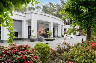 Rustig gelegen temidden van het groen,vindt u deze modernistische eenlaagse villa met een bewoonbare oppervlakte van maar liefst 900 m² op een mooi perceel van circa 10.000 m² voorzien van alle privacy. Via de imposante inkomhal met glazen dakconstructie betreden wij de villa met directe toegang tot de vestiaire, het gastentoilet en het kantoor. Centraal vindt u de woonkamer als één grote, open ruimte, badend in het licht met een prachtig uitzicht op de kleurrijke tuin. Links in de woonkamer bevindt zich de luxueus ingerichte bar, met daaraan grenzend het luxebinnenzwembad met wellnessgedeelte voor het ultieme vakantiegevoel. Door middel van grote raampartijen kan het zwembad indien gewenst afgesloten worden van de leefruimte. Naast het zwembad zijn er 2 ruime slaapkamers met ensuite dressing en badkamer. Rechts van de leefruimte treffen we de hedendaagse eilandkeuken voorzien van alle nodige comfort. Net als alle ruimtes heb je hier via grote schuiframen directe toegang tot het ruime verwarmde terras, dat zich uitstrekt over de volledige achtergevel. Door middel van screens kan het terras afgesloten worden waardoor je hier het hele jaar van kan genieten. De aanwezigheid van een houthaard en een buitendouche maakt het plaatje compleet. Net achter de keuken ligt de berging met bijkeuken. Hier bevinden zich zowel de lift als de trap naar de kelder, deze beslaat overigens dezelfde oppervlakte als de woning en bergt onder meer de technieken. De kelder is via een poort ook toegankelijk aan de zijkant van de woning door middel van een hellend gangpad, waardoor de immense oppervlakte zich perfect leent voorde opslag van goederen of desgewenst kan gebruikt worden als werkruimte. Verder leidt de berging naar de inpandige garage voor 2 wagens en de carport die nog eens ruimte biedt voor hetzelfde aantal wagens. Via een gang bereikt men de overige 2 slaapkamers, een extra badkamer en apart toilet. Deze gang beschikt over een aparte inkomdeur aan de zijkant van de woning. De tuin is volledig rondom het huis minutieus aangelegd en ZW gericht en vloeit naadloos over in het natuurpark “Mechelse Heide.” Verder is er ook een tuinhuis aanwezig. Het domein is volledig omheind en toegankelijk via een geautomatiseerde poort en beschikt over een beveiligingssysteem. Tot slot zijn er zonnepanelen aanwezig met een vermogen van 10200Wp. Deze uitgestrekte villa werd gebouwd met grote aandacht voor een perfecte integratie van de omliggende natuur. Kortom, wonen in een sterk staaltje architectuur, in een oase van groen. Luxe, comfort, rust en esthetiek gaan hand in hand in deze unieke eigendom die eveneens perfect geschikt is voor de uitoefening van een vrij beroep.<br /><br /><strong>Algemene Gegevens – Modernistische Villa</strong>
<ul>
	<li>Ligging: Rustig, midden in het groen</li>
	<li>Bewoonbare oppervlakte: ± 900 m²</li>
	<li>Perceeloppervlakte: ± 10.000 m²</li>
	<li>Oriëntatie tuin: Zuidwest (ZW)</li>
	<li>Volledige privacy</li>
</ul>
<br /><br /><strong>Indeling woning</strong>

<ul>
	<li>Inkomhal: Imposant, met glazen dakconstructie</li>
	<li>Vestiaire</li>
	<li>Gastentoilet</li>
	<li>Kantoor</li>
	<li>Woonkamer: Grote open leefruimte, veel licht, uitzicht op kleurrijke tuin</li>
	<li>Aansluitend: Luxueuze bar</li>
	<li>Binnenzwembad met wellnessgedeelte (afsluitbaar met glazen wanden)</li>
	<li>Keuken: Moderne eilandkeuken met alle comfort</li>
	<li>Directe toegang tot groot verwarmd terras over volledige achtergevel</li>
	<li>Terras afsluitbaar met screens, voorzien van houthaard en buitendouche</li>
	<li>Berging/bijkeuken:</li>
	<li>Lift en trap naar kelder</li>
	<li>Toegang tot inpandige garage (2 wagens) + carport (2 wagens)</li>
	<li>Slaapkamers:</li>
	<li>2 ruime slaapkamers met ensuite dressing en badkamer (naast zwembad)</li>
	<li>2 extra slaapkamers met extra badkamer en apart toilet</li>
	<li>Aparte zij-ingang via gang</li>
</ul>
<br /><br /><strong>Kelder</strong>

<ul>
	<li>Zelfde oppervlakte als woning (±900 m²)</li>
	<li>Toegankelijk via trap, lift en hellend gangpad</li>
	<li>Geschikt voor opslag of werkruimte</li>
	<li>Bevat technische installaties</li>
</ul>
<br /><br /><strong>Buitenruimte</strong>

<ul>
	<li>Professioneel aangelegde tuin rondom</li>
	<li>Naadloze overgang naar natuurpark “Mechelse Heide”</li>
	<li>Tuinhuis aanwezig</li>
	<li>Domein volledig omheind</li>
	<li>Automatische toegangspoort</li>
	<li>Beveiligingssysteem</li>
</ul>
<br /><br /><strong>Techniek &amp; Duurzaamheid</strong>

<ul>
	<li>Zonnepanelen: Vermogen 10.200 Wp</li>
	<li>Verwarming terras</li>
	<li>Lift aanwezig</li>
</ul>
<br /><br /><strong>Bijzonderheden</strong><br /><br />Deze modernistische villa combineert luxe, comfort en rust in een harmonisch geheel dat volledig opgaat in de omliggende natuur. De open architectuur, grote glaspartijen en hoogwaardige afwerking zorgen voor een licht en ruimtelijk gevoel.<br />De aanwezigheid van een binnenzwembad met wellness, een verwarmd terras, zonnepanelen en een lift bieden het hoogste wooncomfort. Dankzij de unieke ligging aan de rand van de Mechelse Heide geniet u van volledige privacy en een prachtig uitzicht.<br />Een uitzonderlijke eigendom waar architectuur en levenskwaliteit samenkomen – ideaal als exclusieve gezinswoning of voor de uitoefening van een vrij beroep.<br />- Maatregelenregister : Er zijn geen maatregelen op dit perceel<br /><br /><br /><strong>Locatie: Mechelen-aan-de-Maas, Maasmechelen</strong><br /><br />Rustig gelegen doch centraal. Faciliteiten zoals scholen, winkels en diensten vindt u in de nabijheid. Als kers op de taart geniet u een vlotte verbinding met invalswegen naar Brussel Antwerpen en Nederland.
