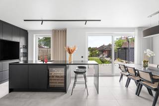 <p>Bent u op zoek naar de perfecte balans tussen een centrale ligging, modern comfort en een sfeervolle, smaakvolle inrichting? Deze recente en trendy 3-gevelwoning uit <strong>2024</strong> biedt het allemaal. Gelegen in de directe nabijheid van scholen en het bruisende centrum, en met een uitstekende verbinding naar de <strong>A12</strong>, geniet u hier van een toplocatie waar mobiliteit en rust hand in hand gaan.</p><p>Dankzij de high-end afwerking, een doordachte indeling en de integratie van een modern <strong>domoticasysteem</strong> is deze woning volledig klaar voor de toekomst.</p><h3>Een sfeervol en warm welkom</h3><p>Bij het betreden van de woning wordt u meteen verwelkomd in de stijlvolle inkomhal met gastentoilet. Doorlopend bereikt u de <em>cozy</em> leefruimte, die warmte en rust uitstraalt—de ideale plek voor een gezellig avondje voor de buis.</p><p>Aansluitend bevindt zich de absolute eyecatcher van het huis: de royale <strong>leefkeuken</strong>. Dit is een ware droom voor elke kookliefhebber. Uitgerust met hoogwaardige toestellen, een ingebouwde <strong>wijnkoeler</strong> en een riant kookeiland, leent deze ruimte zich perfect voor uitgebreid tafelen met vrienden en familie. Wat deze keuken écht uniek maakt, is het panoramische uitzicht op de tuin; een levend schilderij dat in elk seizoen een nieuwe belevenis biedt.</p><p>Praktisch comfort is er ook: de inpandige garage biedt niet alleen plaats voor de wagen, maar fungeert tevens als handige wasplaats en extra berging.</p><h3>Ruimte, comfort en flexibiliteit op de verdiepingen</h3><p>Op de eerste verdieping leidt de nachthal met apart toilet naar drie volwaardige slaapkamers. De <strong>master bedroom</strong> is een luxe suite op zich, compleet met een eigen, op maat gemaakte <strong>dressingkamer</strong>. De badkamer trekt de lijn van hoogwaardige afwerking feilloos door en is voorzien van alle comfort, waaronder een royale <strong>XL-douche</strong>.</p><p>Via een vaste trap bereikt u de reeds geïsoleerde en volledig afgewerkte <strong>zolderverdieping</strong>. Deze doet momenteel dienst als polyvalente ruimte, maar biedt de flexibiliteit om heel eenvoudig omgevormd te worden tot <strong>2 extra slaapkamers</strong> of een riant thuiskantoor.<br /><br /><strong>RICHTPRIJS 595.000€</strong></p><h3>Strakke buitenomgeving</h3><p>Buiten is het genieten in de prachtig aangelegde tuin. De combinatie van de zorgvuldig gekozen beplanting en het strakke terras in <strong>gepolierde beton</strong> geeft het geheel een moderne, architecturale uitstraling en vraagt bovendien weinig onderhoud.</p><h3>De troeven in een oogopslag:</h3><ul><li><p><strong>Bouwjaar 2024:</strong> Volledig up-to-date, energiezuinig en instapklaar.</p></li><li><p><strong>High-end technieken:</strong> Uitgerust met domotica en een slimme, doordachte indeling.</p></li><li><p><strong>Droomkeuken:</strong> Voorzien van luxe-toestellen, wijnkoeler en een groot eiland.</p></li><li><p><strong>Ruimte & Potentieel:</strong> 3 slaapkamers (inclusief dressing) met de mogelijkheid tot 5 kamers dankzij de ingerichte zolder.</p></li><li><p><strong>Toplocatie:</strong> Nabij scholen, centrum en een vlotte verbinding met de A12.</p></li></ul><blockquote><p><strong>Bent u net zo enthousiast als ik?</strong> Laat deze unieke kans niet aan u voorbijgaan en plan vandaag nog uw bezoek.</p></blockquote><p></p>