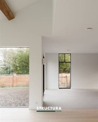 In het centrum van het charmante Brussegem presenteren wij u deze uitzonderlijke driegevelwoning waar verfijning, ruimte en hoogwaardige afwerking harmonieus samenkomen. Een unieke eigendom met landelijke uitstraling en hedendaags design, volledig afgewerkt met premium materialen en oog voor detail.Gelegen op wandelafstand van winkels, school en sportfaciliteiten geniet u hier van een rustige woonomgeving met optimale bereikbaarheid. Deze instapklare woning biedt een perfecte balans tussen luxe, comfort en functionaliteit.IndelingGelijkvloersVia de elegante inkomhal met ingewerkte maatkasten en gastentoilet betreedt u de woning. Links bevindt zich een stijlvol bureau met maatwerkbureau en ingemaakte kasten – ideaal voor wie wonen en werken wenst te combineren.De ruime leefruimte met open keuken en eetgedeelte straalt warmte en rust uit. De gashaard, de hoogwaardige afwerking en de hoge plafonds creëren een bijzonder ruimtelijk en luxueus gevoel.De volledig uitgeruste keuken beschikt over premium toestellen en een exclusief Lacanche-gasvuur als absolute blikvanger voor kookliefhebbers. Aansluitend bevindt zich een praktische berging met extra koelkast en diepvries, toegankelijk zowel via de woning als rechtstreeks van buiten via een deur met codeklavier.Eerste verdiepingVia een elegante eiken trap bereikt u de eerste verdieping. Hier bevinden zich twee slaapkamers (beide +/- 17m²), een apart toilet en een moderne badkamer afgewerkt in microcement met ruime inloopdouche. De overloop is voorzien van geïntegreerde maatkasten voor extra opbergruimte.Tweede verdiepingOp de bovenverdieping bevindt zich de luxueuze master suite met hotelallure. Deze royale ruimte omvat een ruime dressing en een stijlvolle ensuite badkamer met vrijstaand bad, inloopdouche en dubbel lavabomeubel. Ook de technische ruimte is hier discreet geïntegreerd.Karakteristieken- Driegevelwoning met landelijke charme en moderne architectuur- High-end afwerking met zorgvuldig geselecteerde materialen- Designkeuken met exclusief Lacanche-gasvuur- Gashaard in de leefruimte- Hoge plafonds voor extra ruimtelijk gevoel- 2 slaapkamers + luxueuze master met dressing- 2 badkamers- Bureau met maatwerkmeubilair- Berging met extra koelkast en diepvries- Maatkasten geïntegreerd doorheen de woning- Energiezuinige en duurzame technieken- Topligging in het centrum van Brussegem- Bestuursmaatregelen in het maatregelenregister: nee- Verkoop onder btwDeze woning is een toonbeeld van kwaliteit, doordacht design en modern wooncomfort. Elk detail werd zorgvuldig uitgewerkt om een harmonieuze en exclusieve woonbeleving te garanderen.Bent u op zoek naar een luxueus afgewerkte, instapklare woning in het hart van Brussegem?Contacteer ons vandaag nog voor meer informatie of een bezoek ter plaatse en ontdek zelf de klasse en uitstraling van deze bijzondere eigendom via 02 460 80 46 of info@structura.be