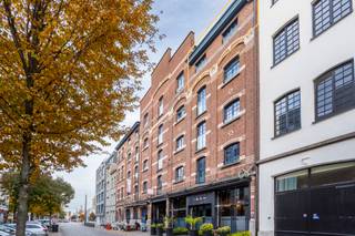 This stylish loft of approx. 173 m² with a terrace of approx. 9 m² is located on the fourth and top floor of a former warehouse that has been completely renovated.<br /><br />The spacious entrance hall leads to the living area, with a staircase leading to the mezzanine where the open kitchen and dining area are located. The characterful, white-painted wooden roof trusses immediately catch the eye here. This space offers direct access to the terrace, which offers a beautiful view of the MAS.<br /><br />The beautiful custom-made kitchen, finished in smoked oak joinery and with beige composite stone worktops, is equipped with high-quality built-in appliances: dishwasher, fridge with freezer, induction hob, combi-oven and convection oven. Adjacent to the kitchen is a functional storage room, ideal for extra storage.<br /><br />The two spacious and fully-fledged bedrooms each have their own designer bathroom, with smoked oak joinery providing a stylish reference to the kitchen.<br />The master bedroom is equipped with a freestanding bathtub, a spacious walk-in shower, a double washbasin and a toilet. The second bedroom has a bathroom with a walk-in shower and washbasin.<br /><br />Oak parquet flooring and black wrought iron interior doors with glass were chosen throughout the flat, providing plenty of light and a refined loft atmosphere.<br />A spacious storage/laundry room with connections for a washing machine and dryer completes the whole.<br /><br />Separate guest toilet.<br /><br />Common charges: 110 Euro.<br />All utilities are to be paid privately by the tenant.<br /><br />Available immediately.