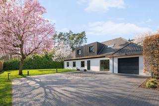 <p>In een rustige, residentiële villawijk bevindt zich deze uitzonderlijke, instapklare villa waar design, comfort en licht centraal staan. Achter de strakke gevel schuilt een verrassend ruime woning met een warme, minimalistische afwerking en hoogwaardige materialen.<br /><br />Grote raampartijen en een doordachte architectuur zorgen doorheen de hele woning voor een unieke beleving van licht en ruimte.<br /><br /><span><strong>INDELING</strong></span><br /><br />U wordt verwelkomd in een imposante inkomhal met vide en maatkasten. Via stijlvolle glazen pivotdeuren bereikt u de lichtrijke leefruimte met gezellige zithoek en ingewerkte haard.<br /><br />De open leefkeuken met strak kookeiland en kwalitatieve toestellen sluit naadloos aan op de eetruimte, die dankzij grote raampartijen uitkijkt op de tuin en het zwembad.<br /><br />Op de verdieping bevinden zich meerdere ruime slaapkamers (5 in totaal). De master suite beschikt over ingemaakte kasten en een luxueuze badkamer met vrijstaand bad, inloopdouche en dubbele wastafel.<br /><br />Daarnaast is er nog een extra badkamer aanwezig.<br /><br /><span><strong>BIJZONDERHEDEN</strong></span><br /><br />- Architecturale villa met overvloed aan natuurlijk licht<br />- Grote raampartijen met directe connectie naar tuin en terras<br />- Zwembad en sauna aanwezig<br />- Inpandige garage en praktische bergruimtes<br />- Airconditioning en moderne technieken aanwezig<br />- Mogelijkheid tot het inrichten van een kantoor of praktijkruimte op het gelijkvloers<br /><br />Een unieke kans voor wie op zoek is naar exclusief wonen met een perfecte balans tussen luxe en functionaliteit.</p>