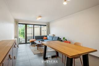 Voor meer info en foto’s, surf naar www.swevers.be – Aan de Luikersteenweg 324 in Hasselt vindt u dit instapklare gelijkvloerse appartement met één slaapkamer, privatieve staanplaats en een ruim terras met achterliggend groen. Het appartement maakt deel uit van een kleinschalig gebouw met slechts vier entiteiten, wat zorgt voor beperkte gemeenschappelijke kosten en een aangename woonomgeving.<br />Met een bewoonbare oppervlakte van 72 m² biedt dit appartement een praktische en lichtrijke indeling. De leefruimte van ca. 26,5 m² vormt het hart van de woning en geniet dankzij de grote raampartij van veel natuurlijk licht en zicht op het terras en het achterliggende groen.<br />Aansluitend bevindt zich de functionele keuken. Verder beschikt het appartement over een ruime slaapkamer van ca. 16 m², een aangename badkamer, een aparte berging en een afzonderlijk toilet. Het terras van 16 m² is een grote troef: hier geniet u volop van de rust en privacy. Het privatief gebruik van een stukje achterliggende tuin is bovendien bespreekbaar. Ook qua comfort zit u goed dankzij de gascondensatieketel en Daikin Perfera lucht-lucht warmtepompen, die zorgen voor energiezuinige verwarming en verkoeling. Winkels liggen op wandelafstand, openbaar vervoer op 120 meter en de E313 op korte afstand. Een ideale kans voor starters, alleenstaanden of investeerders die comfortabel en centraal willen wonen in Hasselt. Voor meer informatie, bel 011 255 155. Bron bewoonbare oppervlakte: EPC – verslag.