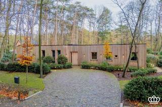 <p><span>Unieke gelijkvloers nieuwbouwvilla, met o.a. ruime en lichtrijke leefruimtes, 4 slaapkamers, 2 badkamers en fietsberging, mooi en rustig gelegen te Kapellenbos op een perceel van ca 5.000 m².</span></p><p><span> </span></p><p><span>INDELING</span></p><p><span> </span></p><p><span>Inkomhal op gepolierde betonvloer met gastentoilet en vestiairekast. De leefruimte, eveneens op gepolierde betonvloer is onderverdeeld in een speel- eet- en zitruimte. De hoge plafonds en grote ramen zorgen voor een overvloed aan natuurlijk licht en bieden een prachtig uitzicht over de tuin. De open keuken is uitgerust met een kookeiland en voorzien van alle hedendaagse inbouwapparatuur. Vanuit de keuken toegang tot een bijkeuken met ingebouwde kasten.</span></p><p><span>De nachthal is bereikbaar via zowel de inkomhal als de leefruimte en voorzien houten beklede muren en een lang dakraam dat voor veel lichtinval zorgt. De masterunit op visgraatparketvloer en onderverdeeld in een slaapkamer met een ruime dressing en een ensuite badkamer. Daarnaast zijn er nog drie extra slaapkamers op visgraatparketvloer voorzien van ingebouwd meubilair en een tweede badkamer. Verder nog een apart toilet, een wasplaats en een technische ruimte (met Vaillant warmtepomp, boiler, ontkalker en zonnepaneleninstallatie) en een inpandige fietsenstalling.</span></p><p><span> </span></p><p><span>Tuin</span></p><p><span>De villa is omgeven door een mooi aangelegde tuin die veel privacy en zoninval geniet en een knus, deels ingesloten terras.</span></p><p><span> </span></p><p><span>Bijzonderheden:</span></p><p><span>- Traditionele gebouwde woning met een hout beklede gevel</span></p><p><span>- Recent gebouwd met duurzame en kwalitatieve materialen, goed gelegen, rustig in het groen en op wandelafstand van de Royal Antwerp Golf.</span></p><p><span>- Unieke bouwstijl die mooi opgaat in de groene omgeving, grote raampartijen, hoge plafonds.</span></p><p><span>- Energiezuinig, warmtepomp met geothermische boring, verwarmen en koelen via vloerverwarming, </span><span>30 zonnepanelen, E-peil negatief: geen K.I. te betalen tem 2029.</span></p><p><span>- Uitgebreid dominicasysteem.</span></p><p><span>- Kruipruimte aanwezig onder de woning.</span></p><p><span> </span></p><p><span> </span></p><p><span> </span></p>