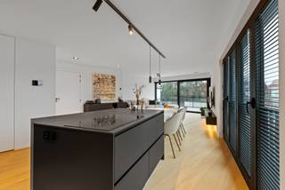 ENERGIEZUINING APPARTEMENT MET LOFT GEVOEL<br /><br />Leefruimte met open keuken, vestiairekasten, vast tv-meubel<br />Keuken met vaatwasser, koelkast, microgolfoven, heteluchtoven, inductie vuur, ingebouwde dampkap, bovenblad uit Dekton, kookeiland, en ontbijthoek.<br />Nachthal op parket met bureau en ingemaakte kasten, gastentoilet en handenwasser.<br />Wasplaats op parket met aansluiting voor wasmachine &amp; droogkast.<br />Hoofdslaapkamer op parket met aanpalende dressing en hoofdbadkamer met ligbad, inloopdouche, dubbel lavabomeubel en toilet.<br />2de slaapkamer op parket met aanpalende 2de badkamer en inloopdouche met enkel lavabomeubel.<br />Zuidwest terras op keramische tegel, gedeeltelijk overdekt, met verlichting.<br />Inclusief garagebox met automatische poort, verlichting en wateraansluitingen (Pidpa &amp; regenwaterput).<br /><br />BIJZONDERHEDEN<br />Volledig opgeschilderd, Lift, Nico home domoticasyteem, allarminstallatie, sunscreens, 6 zonnepanelen, cv op gas, vloerverwarming, dubbele beglazing in aluminium (Reynaers Aluminium) met vliegenhorren &amp; jaloezieën, magneetdeuren, videofoon.<br /><br /><b>POSITIEVE ASPECTEN<br /></b>Loft gevoel<br />Zéér veel lichtinval<br />Gunstige EPC-score<br />Luxueuze afwerking<br />Zuidwest terras zonder niveau verschil<br />Doodlopende straat met zeer veel parkeergelegenheid<br />Op wandelafstand van winkels, scholen &amp; openbaar vervoer