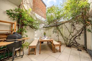 <p><span> </span></p><p><span>Op zoek naar een warme thuis in de stad, met karakter én ruimte? In deze rustige, opkomende buurt tussen Park Spoor Noord en het Rivierenhof woon je heerlijk centraal, omringd door jonge gezinnen, leuke buurtwinkels en pleintjes. Deze charmante woning combineert licht, authenticiteit en een praktische indeling met een gezellige stadstuin als extra troef.</span></p><p><span> </span></p><p><span>Charmant &amp; lichtrijk wonen</span></p><p><span>Binnenkomen doe je via een ruime inkomhal met prachtige cementtegels en een originele trap die meteen de toon zet. De hoge plafonds en sierlijke moluren zorgen voor een open en elegante sfeer die je doorheen de hele woning voelt.</span></p><p><span>Vooraan bevindt zich de leefruimte, een aangename plek waar het daglicht rijkelijk binnenvalt. Dankzij de zuidgerichte oriëntatie en de vele ramen voelt het hier altijd licht en luchtig aan. De warme plankenvloer en de open connectie met de keuken maken dit tot een gezellige plek om te ontspannen of gasten te ontvangen.   Deze keuken is praktisch ingericht met een donker houten look en een natuurstenen werkblad. Hier kook je met plezier, terwijl er nog voldoende plaats is voor een eettafel. Via de dubbele glazen deur wandel je zo naar buiten.</span></p><p><span>De stadstuin is een echte bonus: zuidgericht, onderhoudsvriendelijk en met een charmant groen accent dankzij de begroeiing. Ideaal voor lange zomeravonden of een rustige koffiepauze in de zon.</span></p><p><span> </span></p><p><span>Ruimte voor het hele gezin</span></p><p><span>Op de tussenverdieping vind je een apart gastentoilet met natuurlijk licht – altijd handig.</span></p><p><span>De eerste verdieping voelt ruim en comfortabel aan. Vooraan ligt een grote slaapkamer met hoge plafonds, een mooie, witmarmeren sierschouw en grote ramen. Aansluitend bevindt zich een tweede kamer die perfect kan dienen als dressing, bureau of kinderkamer.</span></p><p><span> </span></p><p><span>De badkamer is verrassend groot en volledig uitgerust: een ligbad, inloopdouche, dubbele lavabo, tweede toilet én plaats voor was- en droogmachine. Hier start en eindigt je dag in alle comfort.</span></p><p><span>Nog een verdieping hoger wachten twee extra slaapkamers, beide volwaardig en aangenaam licht. Achteraan heb je bovendien toegang tot een ruim, zonnig dakterras (niet vergund), waar je in alle rust van de zon geniet.</span></p><p><span>Extra bergruimte nodig? De droge kelder van zo’n ca 32 m² biedt meer dan voldoende plaats.</span></p><p><span> </span></p><p><span>Levendige buurt met alles dichtbij</span></p><p><span>Hier woon je rustig, maar nooit afgezonderd. Op wandel- of fietsafstand liggen zowel Park Spoor Noord als het Rivierenhof – ideaal voor sport, ontspanning of een picknick in het groen. Winkels, scholen en openbaar vervoer zijn vlot bereikbaar, en ook de Ring ligt vlakbij. Een locatie die het beste van stad en buurtgevoel combineert.</span></p><p><span> </span></p><p><span> </span></p>