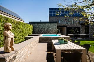 Op een gunstige en vlot bereikbare ligging in Putte bevindt zich deze exclusieve, stijlvol vormgegeven villa, gelegen op een perceel van 998 m². Een eigendom waar ruimte, licht en verfijning samenkomen in een harmonieus geheel, met alle voorzieningen binnen handbereik.<br /><br />Benieuwd naar deze unieke woonbeleving? Ontdek de woning hier via onze cinematische vastgoedfilm!<br /><br />Bij het betreden van de woning wordt u verwelkomd in een lichtrijke inkomhal die meteen de toon zet: stijlvol, doordacht en tot in de puntjes afgewerkt. Hier vindt u tevens een apart gastentoilet, een praktische berging en een op maat gemaakte vestiaire. Aansluitend bevindt zich een eerste bureauruimte, ideaal voor wie wonen en werken naadloos wil combineren. De leefruimte en glaspartijen laten het daglicht rijkelijk binnenstromen en creëren een mooie connectie met de buitenomgeving. De sfeervolle zithoek met gashaard nodigt uit tot ontspannen avonden in alle comfort. Daarnaast beschikt het gelijkvloers over een tweede bureauruimte en een patio, die zorgen voor extra licht en een open, aangenaam ruimtegevoel binnen het open/closed concept van de woning.<br />De leefkeuken beschikt over een indrukwekkend keukeneiland, kwalitatieve toestellen en een hoogwaardige afwerking. Deze elementen maken van deze ruimte een droom voor elke levensgenieter. Hier is bovendien ruim plaats voor een gezellige eethoek met zicht op de tuin. Een plek waar koken, tafelen en samenzijn centraal staan.<br />Ook buiten wordt het luxeverhaal moeiteloos doorgetrokken. Het overdekte terras is voorzien van een open haard zodat u het hele jaar door kan genieten van lange, sfeervolle avonden. Aan alles is gedacht: praktische opbergruimte, een authentieke pizzaoven en een prachtig aangelegde tuin die rust en privacy uitstraalt. Het zwembad, de sauna en de bijhorende douche maken van dit geheel een wellnessbeleving. Op het gelijkvloers bevindt zich bovendien een volwaardige praktijkruimte met aparte ingang en sanitaire voorzieningen. Perfect voor een vrij beroep of zelfstandige activiteit.<br /><br />De eerste verdieping geeft toegang tot vier volwaardige slaapkamers, waaronder een master suite met en-suite dressing. De stijlvolle badkamer is uitgerust met een lavabo, inloopdouche en een vrijstaand ligbad. Eén van de slaapkamers biedt via een vaste trap toegang tot de zolderverdieping, wat extra mogelijkheden creëert. Ook op vlak van energie en technologie voldoet deze woning aan de hoogste standaarden. Met een EPC-label A, 36 zonnepanelen, geïntegreerde muziekinstallatie, alarmsysteem en een conforme elektrische keuring bent u hier volledig klaar voor de toekomst.<br /><br />Kortom, een uitzonderlijke en zeldzame opportuniteit voor wie op zoek is naar een exclusieve, energiezuinige villa met praktijkruimte, vier slaapkamers en een sublieme buitenbeleving in Putte. Contacteer ons voor meer informatie via 0472/22 12 41 of bezoek www.boonstravastgoed.be.<br /><br />Bijzonderheden:<br />- 292 m² bewoonbare oppervlakte<br />- Praktijkruimte met aparte toegang<br />- Hoogwaardige afwerking en architectuur<br />- Energiezuinig (EPC-label A) met 36 zonnepanelen<br />- Zwembad, sauna en buitenbeleving op topniveau