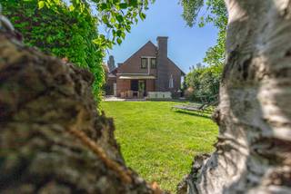 <p>Deze ruime villa met 4 slaapkamers bevindt zich in een residentiële en groene omgeving in Dilbeek, op een mooi perceel van 18a29. De woning onderging in 2015 verschillende renovaties en bevindt zich vandaag in degelijke en verzorgde staat, ideaal voor wie op zoek is naar ruimte, privacy en een combinatie van wonen en werken.</p><p>Via de inkomhal met gastentoilet en vestiaireruimte kom je terecht in de aangename leefruimte met veel natuurlijk licht. De vernieuwde en volledig ingerichte keuken sluit hier mooi op aan en biedt een prachtig zicht op de groene tuin. Dankzij de rustige ligging en de volwassen beplanting geniet je hier van veel privacy en een aangename woonomgeving.</p><p>Op het gelijkvloers bevindt zich daarnaast een praktische bureauruimte en een slaapkamer met douche, wat deze woning ook geschikt maakt voor gelijkvloers wonen of een multifunctionele invulling.</p><p>Een belangrijke troef van deze villa in Dilbeek is de afzonderlijke ingang naar de praktijkruimte. Deze ruimte is momenteel ingericht als schoonheidssalon en beschikt over een wachtruimte en een apart toilet. Ideaal voor een vrij beroep, zelfstandige activiteit of praktijk aan huis.</p><p>Op de eerste verdieping bevinden zich 3 ruime slaapkamers, elk uitgerust met een airco-installatie. Verder zijn er 2 badkamers, een afzonderlijk toilet en een extra zolderkamer die perfect dienst kan doen als hobbyruimte, dressing of extra bergruimte.</p><p>De woning is deels onderkelderd en beschikt over een ruime inpandige garage met voldoende opslagmogelijkheden. Voor de woning is er bovendien ruime parkeergelegenheid voorzien.</p><p>Deze villa combineert een groene en residentiële ligging met een praktische indeling en veel mogelijkheden voor grote gezinnen of zelfstandigen. Dankzij het EPC D en de conforme elektrische keuring geniet je bovendien van extra comfort en gemoedsrust. Ontdek zelf de ruimte, het licht en de rustige omgeving tijdens een bezoek.</p>