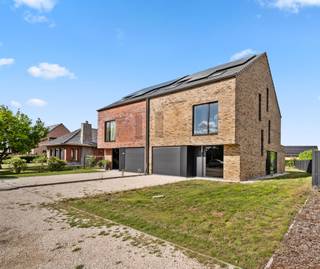 <p><span>Deze nieuwbouwwoning valt onder het btw-regime (21% btw van toepassing op de verkoopprijs). Met circa 289 m2 aan bewoonbare oppervlakte, mogen we wat deze nieuwbouwwoning aangaat, spreken over een zeer ruime woning, die veel mogelijkheden geeft aan thuiswerkers met kinderen. Met 5 kamers die ter beschikking staan op 2 verdiepingen, kan u vlot tegemoetkomen aan alle ruimte-eisen. Logisch staan dan ook 2badkamers ter beschikking, één met bad en inloopdouche en een andere met inloopdouche. Het hele huis is voorzien van energiezuinige vloerverwarming, gevoed door een lucht-water warmtepomp. In deze woning is speciale aandacht gegeven aan de inpandige garage, wat stilaan een zeldzaamheid wordt bij perfect geïsoleerde woningen. Het geheel oog van buiten al heel strak, door het gebruik van de gelijmde bakstenen, het claustra-metselwerk ter hoogte van de dressing in de voorgevel en de grote raampartijen.</span></p>