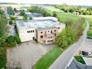 <p><strong>Showroom | Kantoren | Ateliers | Opslag</strong></p>
<p>Op een perceel van 3.927 m² biedt dit gebouw van ongeveer 1.770 m² nuttige oppervlakte een veelzijdige indeling die zeldzaam is op de markt, bewoond sinds de bouw door zijn enige en unieke eigenaar.</p>
<p><strong>Verdeling van de oppervlaktes</strong></p>
<p><strong>Niveau -1</strong><br />Een lichtrijke showroomruimte van 235 m², met een plafondhoogte van 9 m en talrijke lichtkoepels, aangevuld met een inkomhal van ±185 m² alsook sanitair, kleedkamers, traphal en stookplaats (±50 m²).</p>
<p><strong>Niveau 0</strong><br />Bijna 1.220 m², bestaande uit onthaal en kantoren (385 m²), een eerste magazijn van 445 m² onder ±6 m hoogte met sectionale poort, en een tweede magazijn afkomstig van de uitbreiding uit 2006 (390 m², ±5 m hoogte, eveneens met sectionale poort).</p>
<p><strong>Niveau +1</strong><br />315 m² kantoren, met een grondreserve die een toekomstige uitbreiding van ongeveer 200 m² mogelijk maakt.</p>
<p><strong>Technische troeven</strong><br />Het gebouw beschikt over fotovoltaïsche panelen op het dak, gasverwarming voor de magazijnen en de showroom, radiatoren op gasketel voor de kantoren, een gepolierde betonvloer, een gemengde structuur van hout/betonmetselwerk, houten raamkozijnen, een systeem van nachtelijke koeling in de showroom, 2 douches en een alarm.</p>
<p><strong>Toegang &amp; parking</strong><br />Ongeveer 20 parkeerplaatsen verdeeld over twee afzonderlijke toegangen (Avenue Newton en Tienne de la Petite Bilande).</p>
<p><strong>Voorwaarden</strong><br />Verkoop onder de vorm van een Share Deal (overdracht van aandelen van de vastgoedvennootschap, details op aanvraag). Onroerende voorheffing: 9.740 €</p>