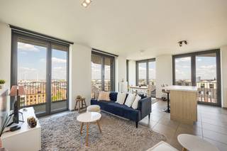 Aan het Schengenplein, in de populaire Cadixwijk op ’t Eilandje, bevindt zich dit instapklare appartement van 82 m² met twee terrassen van samen 23 m2, op de 7de verdieping van residentie Cadiz (2011).<br /><br />De buurt groeide de voorbije jaren uit tot één van de meest aantrekkelijke woonomgevingen van Antwerpen. Je woont hier in een moderne, levendige wijk op wandelafstand van de dokken, het MAS en tal van gezellige horecazaken.<br /><br />Het appartement valt meteen op door zijn lichtinval en praktische indeling. De leefruimte met open keuken is uitgerust met kwalitatieve AEG-toestellen en een centraal keukeneiland, ideaal om te koken en samen te komen. Grote raampartijen zorgen voor een open uitzicht en geven toegang tot twee terrassen, wat extra buitenruimte en een aangename connectie met de omgeving biedt.<br /><br />Verder zijn er twee volwaardige slaapkamers, een moderne badkamer met inloopdouche, een apart toilet en een praktische berging. De ligging op de 7de verdieping zorgt voor extra licht, ruimtegevoel en privacy.<br /><br />Dankzij de recente bouw (2011) en aluminium ramen met hoogrendementsglas geniet je hier van comfortabel en energiezuinig wonen (EPC-label B).<br /><br />Een ondergrondse staanplaats kan aangekocht worden voor €30.000.<br /><br />Voor meer info of een bezoek: 03 225 00 68 of laura@wellimmo.net<br /><br />Bekijk de videotour, plannen,  EPC en elektrische keuring via de Wellimmo-site (documenten).