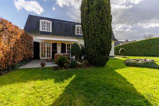 Deze karaktervolle Franse villa straalt charme en klasse uit vanaf het eerste moment. Via de statige inkomhal betreedt u de woning, waar authenticiteit en ruimtegevoel meteen samenkomen. De ruime, lichtrijke leefruimte met prachtig parket vormt het hart van de woning en biedt een warme en uitnodigende sfeer.<br /><br />Aansluitend vindt u een afzonderlijke keuken met aanpalend een handige berging. Daarnaast beschikt de woning over een bijkeuken en sanitaire cel, en een gastentoilet wat extra comfort en functionaliteit biedt. Een afzonderlijk bureel maakt thuiswerken in alle rust perfect mogelijk.<br /><br />Op de verdieping bevindt zich een ruime nachthal die toegang geeft tot vier volwaardige, ruime slaapkamers. De verdieping wordt vervolledigd met een grote badkamer en een afzonderlijk toilet.<br /><br />Verder beschikt de woning over een ruime kelder met voorraadmogelijkheden en een dubbele garage, wat zorgt voor extra bergruimte en praktisch gemak.<br /><br />Buiten geniet u van een aangename tuin waar het heerlijk tot rust komen is. Het terras is uitgerust met een zonneluifel, ideaal om ook op warme dagen comfortabel buiten te vertoeven. Bovendien is er de mogelijkheid om het achtergelegen perceel van circa 1680 m² (zwart gearceerd op de laatste luchtfoto) optioneel bij aan te kopen; de arcering is louter indicatief en biedt geen enkele waarborg omtrent de exacte oppervlakte of afmetingen.<br /><br />Kortom: een prachtige, karaktervolle villa waar rust, ruimte en charme hand in hand gaan.