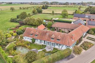 <strong>Prachtige vierkantshoeve met binnenkoer op een uitgestrekt perceel van 1ha43a15ca.</strong> <br />Dit bijzonder vastgoed is gelegen op de Knipscheerstraat 50 in het rustige Alken; omgeven door weilanden én met een vlotte verbinding naar belangrijke invalswegen. Het pand is oorspronkelijk opgetrokken rond 1850 en door de huidige eigenaars grondig gerenoveerd in de jaren '90 met behoud van originele elementen. <span>Kwaliteit, privacy en authenticiteit staan hier centraal. Het pand biedt zeer veel mogelijkheden gezien de beschikbare bewoonbare oppervlakte van 356m² (woongedeeltes), de aanwezigheid van de stallen en van het bijkomende woonhuis (zonder busnummer).</span><br /><br />De imposante toegangspoort leidt naar de binnenkoer die het woongedeelte verbindt met de stallingen en autobergplaats aan de rechterzijde en een tweede woongelegenheid die momenteel dienst doet als bureel.<br /><br />Het <span>eerste woongedeelte</span> is ingedeeld in een inkomhal met gastentoilet en toegang tot de ingerichte keuken. De woonkamer bestaat uit een eethoek met zitplaats en open haard, een bar en een extra zitgedeelte. Deze ruimtes zijn verdeeld over verschillende niveaus. Prachtig zicht op het groen en de vijver. Verder is er nog een wasplaats/berging en een bureel. Op de eerste verdieping is er een ruime overloop die dienst doet als extra TV-kamer, de masterbedroom met dressing en ruime badkamer, een tweede slaapkamer met sanitaire voorzieningen en een 3de slaapkamer die zowel toegankelijk is via de masterbedroom als via het tweede woongedeelte. De woning is deels onderkelderd en hierin zijn de CV-ketels ondergebracht.<br /><br />Het <span>tweede woongedeelte</span> is gelegen aan de achterzijde van het pand en heeft een aparte ingang. Dit woongedeelte is ingedeeld in een inkomhal met een gastentoilet, een woonkamer (momenteel ingericht als bureel en een keukenhoek). Op de eerste verdieping is er een badkamer en twee slaapkamers. Er is een derde kamer die toegang biedt tot de hoofdwoning. <br /><br />De charmante binnenkoer is de plaats bij uitstek om in alle privacy tot rust te komen en te genieten op één van de (overdekte) terrassen.<br />In de ruime <span>garage</span> kan men minstens twee wagens parkeren. De <span>stallingen</span> hebben in het verleden steeds gediend als atelier en kunnen na renovatie en het verkrijgen van een vergunning verder naar wens ingericht worden.<span><br /><br /></span>De tuin is volledig omheind en aangelegd in Engelse stijl en biedt plaats aan meerdere terrassen. De weide en stal zijn ideaal om dieren te houden. Tot slot is er nog een boomgaard met meerdere fruitbomen. <br /><br />De elektriciteit is conform aan de strenge normen van het AREI. <br />Zeer gunstig EPC label C (dubbele verwarmingsinstallatie op aardgas).<br /><br />Kortom: ben jij op zoek naar een authentieke hoeve op een weids perceel in een uiterst groene omgeving? <span>Neem dan vandaag nog contact op voor een bezichtiging en ontdek dit uniek pand met eigen ogen. <br /><br />Wij <strong>ontzorgen</strong> je ook voor de <strong>verkoop van je huidige woning</strong>! Voor meer uitleg helpen we je graag verder.</span>