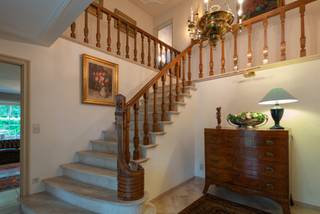 <p>Deze karaktervolle klassieke villa werd in 1981 gebouwd door architect Laporta in opdracht van de huidige eigenaars. De woning biedt royale leefruimtes, 5 tot 6 slaapkamers, 3 badkamers en is gelegen op een prachtig perceel van 5.233m². De combinatie van duurzame materialen, ruime vertrekken en een uitzonderlijke groene ligging maakt dit een bijzonder eigendom. De villa grenst aan de Halse Bossen en het Drijhoekbos, samen goed voor een natuurgebied van ca. 200 ha.</p>
<p><strong>GELIJKVLOERS<br /></strong>Via de statige inkomhal op travertin met grote trappartij, gastentoilet en handenwasser betreden we de woning. Aan de rechterzijde bevindt zich het bureel en centraal de keuken. De woonkamer bestaat uit verschillende sfeervolle delen met een leeshoek, TV-hoek aan de open haard in Franse zandsteen en een eethoek met toegang tot het terras en de orangerie. De orangerie op travertin beschikt over vloerverwarming en automatische sunscreens. De ruime keuken met ontbijthoek is voorzien van een granieten werkblad, vaatwasser, heteluchtoven en dubbele spoelbak en sluit aan op de koeleberging en wasplaats. De dubbele garage beschikt over een automatische poort, ingemaakte kastenwand en uitgietbak. Via een overdekte doorgang is er toegang tot de 3de garage.</p>
<p><strong>1STE VERDIEPING<br /></strong>De statige trappartij brengt ons naar de overloop op Brabo parket met linnenkasten, nachttoilet en handenwasser. De mastersuite omvat een dressing, vernieuwde badkamer met dubbele lavabo, spiegelkasten, inloop-regen-douche en toilet, aangevuld met 2 slaapkamers of extra dressingruimte. De 3de en 4de slaapkamer beschikken over een gemeenschappelijke badkamer met lavabo, bad/douchecombinatie en toilet. De polyvalente ruimte is momenteel ingericht als woonkamer met kasteelhaard, bar, balkon en bergkamer.</p>
<p><strong>2DE VERDIEPING<br /></strong>De vaste trap leidt naar een overloop, een 6de slaapkamer met eigen douchekamer én een zeer ruime zolder van 110m² met tal van mogelijkheden.</p>
<p><strong>KELDER<br /></strong>De kelderverdieping bestaat uit 2 delen en biedt een bergruimte, een technische ruimte en toegang tot de kruipkelder.</p>
<p><strong>TUIN<br /></strong>De prachtig aangelegde zuidwest tuin biedt 100% privacy en beschikt over een ruim terras, een vijverpartij, tennisterrein en 3 tuinhuizen.</p>
<p><strong>BIJZONDERHEDEN<br /></strong>Rolluiken, tuinverlichting, schrikverlichting, tuinalarm, tennisveld, automatische toegangspoort, cv op aardgas, vloerverwarming, thermostatische kranen, dubbele beglazing, schrijnwerk in hout, vaste vliegenhorren, alarm met sensoren, raamcontacten en deurcontacten, alsook camerabewaking.</p>
<p><strong>POSITIEVE PUNTEN<br /></strong>Royale ruimtes<br />Tijdloze bouwstijl<br />Zuidwest oriëntatie<br />Duurzame materialen<br />Prachtig aangelegde tuin<br />Ca. 60,90 meter straatbreedte<br />Op wandelafstand van natuurgebied<br />Nabij winkels, scholen en openbaar vervoer</p>