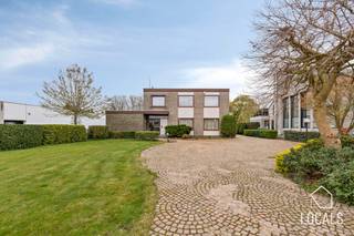 Zeer goed onderhouden architectenwoning op een toplocatie met uitvalbasis naar alle voorzieningen, winkels en aansluiting met hoofdwegen. Daarentegen geniet u achteraan van een rustig, open en groen uitzicht wat zorgt voor een oase van rust en privacy. De woning beschikt over een gunstig EPC-label C, dubbele beglazing, alarm, een nieuwe condenserende ketel op stookolie van 2022, lucht-lucht warmtepompen in verschillende ruimtes en een bruikbare vloeroppervlakte van maar liefst 315m2.<br /><br />Indeling:<br />Via de voorzijde van de woning betreedt u de inkomhal, die toegang geeft tot het architectenatelier, het bureel, een opslagruimte en een gastentoilet. Via de rechterzijde komt u in de privé-inkomhal, vanwaar u de lichtrijke leefruimte bereikt met zicht op de tuin, evenals de volledig geïnstalleerde keuken. Heel de woning is afgewerkt met hoogwaardige materialen. Zowel het werk- als het privégedeelte zijn intern met elkaar verbonden. Op de eerste verdieping geeft de nachthal toegang tot 4 volwaardige slaapkamers. Verder vindt u hier een badkamer en een apart toilet. Daarnaast beschikt de woning over een kelder. Het pand is uitermate geschikt voor meerdere commerciële doeleinden, kangoeroe woning...<br /><br />Buiten beschikt de woning over een overdekt terras met vijver, evenals een ruime oprit die doorloopt tot achteraan, met toegang tot de praktische garages en opslagruimtes. De tuin is zuidgericht en achteraan bevindt zich een wandelpad, vanwaar ook toegang wordt geboden tot de tuin. <br /><br />G-score: A – P-score: A. <br />Voor info of bezichtiging: 054 23 53 83 of info@localsvastgoed.be