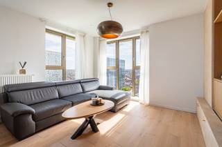 Dit appartement bevindt zich in de gegeerde Cadixwijk, pal naast het Eilandje. Hier woon je op wandelafstand van gezellige restaurants, bars en het Kempisch Dok, terwijl ook Park Spoor Noord vlakbij ligt. Dankzij de nieuwe tramverbinding, de heraanleg van de kaaien en de komst van het nieuwe ziekenhuis is deze buurt vandaag één van de meest populaire plekken om te wonen of te investeren in Antwerpen. Het appartement ligt op de 14de verdieping van de moderne residentie Doctoren (2022) en biedt een adembenemend uitzicht over de skyline van Antwerpen. De kamerhoge ramen zorgen voor overvloedig licht en een warme sfeer. De leefruimte met open keuken is praktisch en stijlvol ingericht en geeft uit op een zonnig privé-terras, perfect om te ontspannen met zicht over de stad. Verder zijn er twee slaapkamers, een verzorgde badkamer, een berging, een aparte gastentoilet en een private kelderruimte. Als extra troef is er het gemeenschappelijke dakterras met fenomenaal panorama over Antwerpen – dé plek bij uitstek voor gezellige momenten in openlucht of om even helemaal tot rust te komen. Meer info? www.walls.be - Epc: 66 kWh/m2 – E-peil: E42, P-score: C, G-score: C, Stedenbouwkundige gegevens in aanvraag