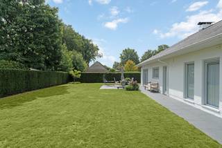 Deze eigendom is zeer verzorgd en is gelegen op een fraai aangelegd perceel. De woning is perfect geschikt voor levenslang wonen, met extra mogelijkheid tot uitbreiding op de bovenverdieping. <br /><br />Via de ruime inkomhal met apart toilet betreedt u de woning. De L-vormige leefruimte is lichtrijk door het gebruik van de vele ramenpartijen. <br />Aparte keuken voorzien van de nodige toestellen en ruimte voor het plaatsen van een extra eettafel. Aansluitend deze ruimte bevindt er zich een praktische bergruimte. De nachthal geeft toegang tot 2 ruime slaapkamers en praktische badkamer met hoekbad en dubbele lavabo. <br />In de woning is een inpandige garage voorzien. Deze geeft enerzijds toegang naar de achtertuin en anderzijds de mogelijkheid met een vlizotrap de zolder te betreden. Deze kan nog afgewerkt worden tot extra leefruimte.<br /><br />De tuin is zeer verzorgd, volledig omheind en voorzien van een elektrische toegangspoort. Op het vernieuwde ruime terras is het zalig vertoeven. Alsook is er een ruim tuinhuis aanwezig, ideaal voor het opbergen van tuinmateriaal.<br /><br />Bijzonderheden:<br />- Goed onderhouden eigendom op centrale locatie <br />- Aanwezigheid van 10 zonnepanelen<br />- Recente warmtepompboiler van 270l + verwarmingsketel<br />- Geboorde waterput aangesloten op zowel de buitenkant als de binnenkant van de woning<br />- Vernieuwde badkamer + vloeren<br />- Rolluiken