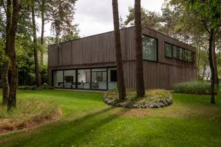 Op een prachtige locatie in Schilde bevindt zich deze unieke, moderne villa op een perceel van 3.848 m², omringd door natuur, rust en privacy.<br /><br />De woning werd ontworpen met oog voor esthetiek, comfort en duurzaamheid, en springt meteen in het oog dankzij haar moderne architectuur met warme gevelafwerking in hout. De voorgevel straalt ingetogen elegantie uit, waarbij ramen subtiel schuilgaan achter verticale houten latten, wat zorgt voor een strak en harmonieus geheel.<br /><br />Bij aankomst leidt een uitnodigend pad u naar de formele inkom van de woning, waar een hal met royale plafondhoogte en een elegante traphal u verwelkomt. Achter een ingewerkte kastenwand bevinden zich een gastentoilet en een vestiaire, beiden discreet en stijlvol geïntegreerd in het ontwerp. Deze inkomruimte zet meteen de toon voor wat volgt: een woning waarin ruimte, licht en functionaliteit centraal staan. De leefruimte vormt het kloppende hart van het huis en wordt gekenmerkt door grote raampartijen die de natuur als het ware naar binnen trekken. De zithoek is ruim en geniet van een indrukwekkende plafondhoogte. Een ingebouwde houthaard achter glas zorgt hier voor extra sfeer en warmte. Aansluitend bevindt zich de eetkamer, centraal gelegen tussen de zitruimte en de open keuken, en perfect voor gezellige diners. De keuken zelf is volledig uitgerust met hoogwaardige toestellen en werd stijlvol geïntegreerd in een strakke kastenwand en in het grote kookeiland. Achter de keuken bevindt zich een praktische berging met wasplaats.<br /><br />Via de leefruimte heeft u toegang tot de patio: een intieme, zuidgerichte buitenruimte met een ruim terras en een prachtig aangelegde zwemvijver. Deze afgesloten plek vormt een oase van rust en biedt volledige privacy, ideaal om te ontspannen of gasten te ontvangen in de zomer. De patio is uitsluitend toegankelijk via de leefruimtes, wat zorgt voor een unieke verbondenheid tussen het interieur en het exterieur, zonder afbreuk te doen aan de privacy van de woning zelf.<br /><br />Vooraan op het gelijkvloers bevindt zich een aparte kamer die perfect kan dienen als praktijkruimte, bureau of extra slaapkamer. Deze ruimte beschikt over een eigen badkamer met douche en lavabo, waardoor ze ook geschikt is voor gasten of voor professioneel gebruik. Daarnaast vinden we nog een fitnessruimte/bureelruimte terug op het gelijkvloers.<br /><br />Op de verdieping vinden we een zeer ruime bureauruimte die eenvoudig kan worden opgedeeld in twee volwaardige slaapkamers. De nachthal biedt toegang tot een apart nachttoilet. De master bedroom is een waar toevluchtsoord, voorzien van een ingemaakte dressing en een luxueuze en-suite badkamer. Deze badkamer beschikt over een inloopdouche, een ligbad, een dubbele lavabo met spiegelkast en een ingebouwde sauna, waardoor u elke dag kan genieten van wellness in eigen huis.<br /><br />De tuin rondom de woning is doordacht aangelegd in harmonie met de bosrijke omgeving. Het terrein is natuurlijk, met mooie graszones die overgaan in het omringende groen, en biedt een perfecte balans tussen openheid en beschutting. De aparte garage is volledig in dezelfde stijl opgetrokken als de woning, met plaats voor twee wagens en extra bergruimte.<br /><br />Deze woning is een uitzonderlijk aanbod voor wie houdt van moderne architectuur, natuurlijke materialen en rust, zonder in te boeten op comfort, luxe en functionaliteit. Een zeldzaam pareltje in het residentiële hart van Schilde.