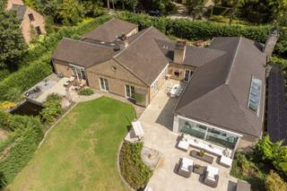 <strong><span>Exclusieve laagbouwvilla op 2.191m² met 4 slpk / 3 bdks en binnen-en buitenzwembad</span></strong><br /><br />Zeer rustig gelegen in een residentiële buurt grenzend aan het Zoerselbos bevindt zich deze uitzonderlijke villa met hoogstaande afwerking en een waaier aan luxevoorzieningen, ingericht door Joris Van Apers.<br /><br />Geniet van ultiem wooncomfort op een prachtige locatie, waar ruimte, ontspanning en verfijning samenkomen. De woning onderging grondige renovaties en uitbreidingen in zowel 1998 als 2010. <br /><br />Inkomhal met toegang tot de ruime L-vormige woonkamer (45m²) op Italiaanse eiken parket met een massieve handgemaakte schouw. Gastentoilet op exclusieve Azul Bahia granieten vloer. <br /><br />De leefkeuken (37m²) is een absolute eyecatcher: een semi-professionele ruimte, uitgerust met o.a. een teppanyaki, wok, friteuse, inductiekookplaat met vijf zones, dubbele dampkappen, professionele kraan, dubbele spoelbak, stoomoven, twee heteluchtovens, een koelcel, twee wijnkoelers, een ontbijttoog en een vermaler. Het werkblad is in stijlvol Marbrinoise. <br /><br />De biljartkamer (39m²) of extra woonkamer op Bourgondische natuursteen is uitgerust met high-end muurbekleding, een open haard en oude Spaanse kasteeldeuren. Deze ruimte is tevens geschikt als praktijkruimte. <br /><br />Via de royale nachthal bereikt u een aparte wasruimte, een vernieuwde badkamer met losstaand ligbad, wastafel, handdoekdroger en 4 slaapkamers. <br />Slpk 1 (18m²) op parket in Italiaanse notelaar met dressing, ensuite badkamer (2010: dubbele wastafel, ligbad, toilet, handdoekdroger) én directe toegang tot een ontspannend en afgesloten terras met vijver en verschillende fonteinen. <br />Slpk 2 (16m²) op parket met dressing en ensuite badkamer met toilet, inloopdouche, wastafel en handdoekdroger. <br />Slpk 3 (14m²) en slpk 4 (18m²) zijn afgewerkt met parket, waarbij slaapkamer 4 beschikt over een ingemaakte kast. <br /><br />Deze villa beschikt over een ruim binnenzwembad met directe toegang via schuifdeuren tot het terras, waar elektrische verwarming en zonnetenten voor extra comfort zorgen. Aansluitend aan het zwembad bevindt zich een wellnessgedeelte met sauna, douche en toilet. <br /><br />Prachtige aangelegde tuin met buitenzwembad en meerdere terrassen. Het perceel is volledig omheind en toegankelijk via een automatische poort. Er zijn meerdere autostaanplaatsen voorzien langs een verlichte oprit, alsook een werkplaats/schuur met zwembad- en vijverinstallatie. <br /><br /><span>Extra:</span> <br />* EPC B <br />* 30 zonnepanelen (2021) met batterij <br />* Warmtepomp buitenzwembad (2025) <br />* CV op stookolie (2012) <br />* Diverse bergzolders <br />* Hobbykelder (66m²) <br />* Drie elektrische zonnetenten <br />* Openhaardschouwen met afzuiging, blaasbalg en timer (rookvrij) <br />* Inbraakwerend dubbel gelaagd dubbele beglazing <br /><br />Elektrische keuring en asbestattest in aanvraag.