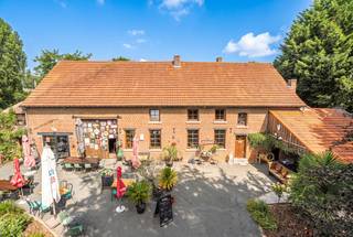 Vous êtes à la recherche d’un bien de caractère offrant de l’espace et de nombreuses possibilités ? Cette propriété unique mérite certainement une visite. Située sur un magnifique terrain de 1.228 m², elle combine une spacieuse maison familiale avec un espace polyvalent authentique.
Dès l’arrivée, le charme de la cour intérieure, les grandes terrasses et le jardin soigneusement entretenu attirent immédiatement l’attention. Grâce à son orientation nord-ouest, vous profitez à différents moments de la journée du soleil et de l’ombre, idéal pour apprécier pleinement les extérieurs tout au long de l’année.
Avec une superficie habitable de 281 m², la maison dispose d’un vaste espace de vie, d’une cuisine équipée, de trois chambres à coucher de belles dimensions, de deux salles de bains ainsi que de plusieurs espaces polyvalents pouvant être aménagés selon vos envies.
L’espace polyvalent constitue sans aucun doute l’atout majeur de cette propriété. Les poutres en bois apparentes, les murs en briques authentiques et les finitions chaleureuses créent une ambiance unique, devenue rare aujourd’hui. Cet espace plein de caractère offre de nombreuses possibilités : pièce de vie supplémentaire, atelier, espace de loisirs ou espace professionnel.
Les extérieurs représentent également un véritable atout. Le grand jardin, les différentes terrasses et l’environnement verdoyant en font un lieu idéal pour se détendre en toute tranquillité ou recevoir des invités. Malgré son cadre rural, la propriété se trouve à proximité des commerces, des écoles, des transports en commun et des principaux axes routiers vers Bruxelles.
La maison est équipée d’un chauffage central au mazout et bénéficie d’un label EPC E, offrant au futur propriétaire la possibilité d’améliorer davantage ses performances énergétiques.
Située en zone d’habitat à caractère rural, cette propriété offre une combinaison exceptionnelle de charme, d’espace et de potentiel dans un emplacement recherché à Sint-Pieters-Leeuw.
Un bien de cette qualité se présente rarement sur le marché. Contactez Claes &amp; Willems pour plus d’informations ou pour organiser une visite sur place.
