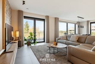 Voor meer info en foto’s, surf naar [www.swevers.be](http://www.swevers.be) — Dit instapklare appartement uit 2025 in Residentie Zwanenpark heeft een bewoonbare oppervlakte van 100 m² en bevindt zich op de eerste verdieping aan Kolmen 32A bus 4, centraal in Tessenderlo. Winkels, restaurants, scholen en openbaar vervoer liggen op wandelafstand, terwijl de snelweg zich op slechts 3,5 km bevindt. De lichtrijke leefruimte van 36,89 m² sluit direct aan op de praktische keuken van 9,11 m². Brede raampartijen geven toegang tot het ruime, westgerichte terras van 12,98 m² waar u geniet van de avondzon. Via de nachthal bereikt u twee slaapkamers van 12,03 m² en 10,02 m², de badkamer met ligbad en twee afzonderlijke toiletten. Met een inloopkast, wasberging, kelderberging van 3,45 m², lift, airco, alarm en een inbegrepen autostaanplaats geniet u van compleet wooncomfort. Maandelijkse kosten: € 112. Bel voor een afspraak naar 011 255 155. Bron bewoonbare oppervlakte: EPC-verslag.