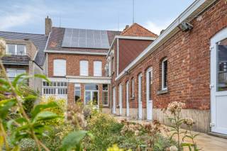 Eclectisch burgerhuis met landelijke verzichten op 2659 m² in centrum Kuurne.<br /><br />Reeds 4 generaties zijn gehuisvest in deze karakterwoning. Sinds 1928 is deze bewoond en altijd onderhouden door deze familie. Nu verkoopt de familie dit prachtig en echt logisch ingedeeld huis.<br /><br />Statige inkom met opvallende trappenhal met een glaskoepel (glas in lood), marmerafwerkingen en een uitzonderlijk schilderij van de Vlasserstreek. Een aparte wachtruimte of bureau is voorzien, alsook nog een oud telefoon-kamertje (momenteel vestiaire). De inkom loopt door tot aan de achterliggende keuken.<br />Aan de rechterzijde van de woning is er een authentieke leefruimte. Hoge plafonds, uitzonderlijk parket en een tussendeur met uniek gekleurd glas (glas-in-lood, met de 4 seizoenen uitgebeeld).<br /><br />In de uitbouw is er een grote keuken. Alle nodige toestellen en plaats om ook hier een grote eettafel te plaatsen. Verder is er aansluitend een groot terras en achteraan het huis verschillende bergingen.<br /><br />Het verdiep bevat 5 slaapkamers en een badkamer (douche en bad) op de gang is er een apart toilet. Een vaste trap brengt ons naar het zolderverdiep. Deze is niet in gebruik en kan zeker nog dienst doen voor extra slaapkamers, hobbykamers,.. De zolder vloer is geïsoleerd.<br /><br />Verder heeft een woning een zeer ruime en droge kelder en een diepe en hoge garage.<br /><br />Een goeie oriëntatie is verzekerd maar vooral dit landelijk verzicht maakt deze eigendom zeer speciaal. Achteraan is er een klein landhuisje die dienst doet als schuilhok voor de dieren en tuingerief.<br /><br />PLUSPUNTEN:<br />+ uitzonderlijk vastgoed met een zeer rijke geschiedenis<br />+ logische indeling<br />+ zonnepanelen, bijna volledig dubbele beglazing aanwezig, isolatie en overal CV op gas.