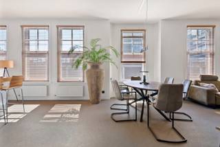 This second-floor apartment is a modern gem in the heart of the city, accessible via lift or an authentic staircase.
Upon entering, the bright living area stands out thanks to large windows and high ceilings. All windows feature high-quality light walnut blinds, adding warmth and privacy. The adjoining Bulthaup kitchen with island includes premium appliances: combi oven, induction hob with designer extractor (Venduro), dishwasher, refrigerator, separate freezer and wine cooler.
A practical storage room with washer and dryer connections, a cloakroom and a separate guest toilet complete the space.
The main bedroom has an en-suite bathroom and dressing room. Two additional full-sized bedrooms—one currently used as an office—and a second stylish bathroom are also present.
In the basement, there is a private storage unit and bicycle room. The apartment is equipped with a lift, video intercom, condensing gas boiler and a 160-litre hot water tank.
Located in the Theatre District, in the city centre, close to shops and amenities, with easy access via the Leien and nearby parking options.