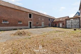 Voor meer info en foto’s, surf naar www.swevers.be – Deze karaktervolle, te renoveren vierkantshoeve uit 1935 aan Pastorijstraat 2 in Gingelom biedt een uitzonderlijke combinatie van ruimte, rust en potentieel. Met 262 m² bewoonbare oppervlakte, zes slaapkamers en een perceel van maar liefst 4 ha 7 a 10 ca vormt deze eigendom een interessante basis voor landelijk wonen, dieren aan huis of een toekomstig project zoals een B&B, mits de nodige vergunningen. Op het gelijkvloers bevinden zich een living met aansluitende eetkamer, een keuken van 16,40 m², badkamer, wasruimte en apart toilet. De eerste verdieping telt zes slaapkamers en biedt volop mogelijkheden om de indeling tijdens de renovatie naar eigen wens aan te passen. De pvc-ramen met dubbele beglazing dateren van de jaren negentig. Een grote troef zijn de bijgebouwen rond de typische centrale binnenkoer. Meerdere stallen, bergingen en een indrukwekkende schuur van circa 257,60 m² bieden ruimte voor opslag, hobby’s, dieren of een mogelijke herbestemming. Het uitgestrekte perceel met noordoostelijke oriëntatie wordt omringd door groen en open velden. Tegelijk blijft de bereikbaarheid uitstekend: openbaar vervoer ligt op circa 210 meter, de snelweg op ongeveer 3 km en de E40 bevindt zich vlakbij. Winkels, horeca en ontspanning zijn eveneens vlot bereikbaar. Voor meer informatie, bel 011 255 155. Bron bewoonbare oppervlakte: EPC – verslag. Dit pand is onderworpen aan de renovatieverplichting van de Vlaamse overheid voor residentiële gebouwen (behoudens bij sloop binnen 5 jaar na de aankoop). Consulteer voor meer informatie de website van het Vlaams Energie- en Klimaatagentschap via https://www.vlaanderen.be/een-huis-of-appartement-kopen/renovatieverplichting-voor-residentiele-gebouwen.