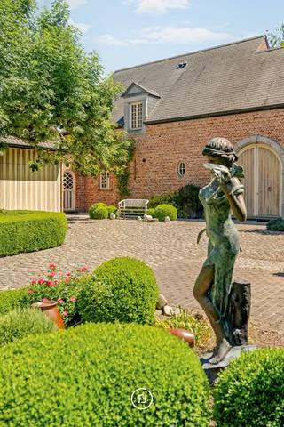 Exclusieve koetsierswoning met zwembad op de Heikant<br /><br />Op de grens tussen Berlare en Zele bevindt zich deze karaktervolle koetsierswoning uit 2003, discreet gelegen in een groene en rustige woonomgeving.<br /><br />De woning biedt ca. 487 m² bewoonbare oppervlakte en combineert royale leefruimtes met een tijdloze landelijke architectuur. Rond de centrale koetsiersgang bevinden zich onder meer een lichtrijke leefruimte met gashaard, een volledig uitgeruste keuken met ontbijthoek, bureauruimte, leeskamer, dubbele garage en vijf slaapkamers.<br /><br />Buiten geniet u van een verwarmd zwembad, ruime terrassen en een prachtig aangelegde tuin die maximale privacy garandeert.<br /><br />Extra troef: de naastgelegen schuur, achterliggende weides en de vooraan gelegen renovatiewoning kunnen optioneel worden mee aangekocht. Ideaal voor paardenliefhebbers, een vrij beroep, kangoeroewonen of wie op zoek is naar bijkomende ruimte en mogelijkheden.<br /><br />Een unieke eigendom voor wie waarde hecht aan rust, privacy en kwalitatief wonen in het groen.