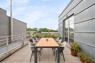 Op een toplocatie aan de Nieuwe Kaai in Turnhout bevindt zich deze karaktervolle fabrieksloft van ca. 102 m², gelegen op de 5de verdieping van ‘Anco B2’, het voormalige hoofdgebouw van de bekende Anco-pastafabriek. Het gebouw dateert uit de periode 1950-1960 en werd met respect voor zijn industriële karakter gerenoveerd, waarbij de typische architectuur en authentieke uitstraling maximaal behouden zijn gebleven.<br /><br />De loft onderscheidt zich door zijn hoge plafonds, aangename lichtinval en prachtige vergezichten. Daarnaast beschikt het appartement over maar liefst twee terrassen, waaronder een ruim zuidgericht terras, waar je heerlijk van de zon en het uitzicht kunt genieten.<br /><br />De indeling omvat een ruime en lichtrijke woonkamer met parketvloer, een aangename leefkeuken uitgerust met een vaatwasser, inductiekookplaat, koelkast en combi-oven, twee slaapkamers en een ruime badkamer met ligbad/ douche, dubbele lavabo in meubel en een toilet.<br /><br />Bijzonderheden:<br />*Lage gemeenschappelijke lasten/ maand! <br />*2 terrassen, waaronder een ruim zuidgericht terras<br />*Hoge plafonds en veel natuurlijke lichtinval<br />*Parketvloer in de woonkamer<br />*Lift aanwezig<br />*EPC-label B<br />*Gelegen op een toplocatie aan de Nieuwe Kaai<br />*Karaktervolle industriële architectuur met behoud van de authentieke uitstraling