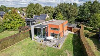 Welkom in de Lovelddreef, een unieke kans om riant en instapklaar te wonen in het felbegeerde, residentiële Heusden. Deze vrijstaande villa (bouwjaar 1993) onderscheidt zich door haar opvallende architectuur naar de hand van arch. Fritz Schaffrath in warme rode baksteen en bevindt zich op een indrukwekkend perceel van 1.788 m². Hier vloeien doordacht design, leisteen accenten, overvloedige lichtinval en weidse natuur naadloos in elkaar over.<br /><br />Bij het betreden van de woning via de stijlvolle inkomhal valt meteen de royale bruikbare oppervlakte van 263 m² op. De leefruimtes worden getypeerd door een speelse split-level indeling, plafondafwerking in karaktervol zichtbeton en indrukwekkende glazen raampartijen van vloer tot plafond. De sfeervolle zithoek is voorzien van een strakke open haard en parketvloer, terwijl de verhoogde eetruimte is ondergebracht in een spectaculaire glazen uitbouw met panoramisch zicht op de tuin en achterliggende velden. Om het hele jaar door van een optimaal binnenklimaat te genieten, is de achtergevel voorzien van hoogwaardig zonnewerend glas.<br /><br />Via de glazen schuifdeuren stapt u zo het riante houten terras op, de perfecte plek voor uitgebreid tafelen en ontspannen in alle rust. De omheinde, groene tuin met karaktervolle volwassen bomen garandeert 100% privacy en biedt een veilige speelomgeving voor kinderen.<br /><br />De strakke, moderne keuken staat in directe verbinding met de leefruimte en is voorzien van speelse doorkijkjes naar het groen. Via de stijlvolle traphal bereikt u de lichtrijke overloop op de eerste verdieping, die prachtig wordt verlicht door een natuurlijke lichttunnel.<br /><br />Op de bovenverdieping bevinden zich vier volwaardige slaapkamers en twee badkamers. Bijzonder troefrijk voor gezinnen zijn de twee aaneengeschakelde kinderkamers die rechtstreeks met elkaar verbonden zijn via een schuifdeur. Dit biedt kinderen of tieners de unieke mogelijkheid om hun slaapkamer direct te combineren met een eigen speel-, studeer- of ontspanningsruimte. Een derde, afzonderlijke (kinder)kamer vervolledigt het plaatje en biedt heel wat mogelijkheden. De master suite is eveneens een blikvanger: met zijn royale oppervlakte, zicht op het groen en met een adembenemende en-suite badkamer waar het ligbad pal voor een groot raam is geplaatst, met direct zicht op de tuin en de boomtoppen. Elke slaapkamer is voldoende ruim om dubbele bedden te plaatsen.<br />Aan comfort en functionaliteit is tot in de puntjes gedacht: een ruime oprit met een brede dubbele carport, een handige buitenberging, een droge voorraadkelder, een waterontharder en een geïntegreerde surround installatie.<br /><br />Kortom, hier combineert men architecturale klasse en instapklaar gezinscomfort met een droomperceel in het groen. We nodigen u van harte uit voor een individueel en persoonlijk begeleid bezoek.<br /><br />Belangrijk: de vermelde prijs is een richtprijs!<br /> 