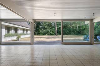 Op een prachtig, bosrijk perceel nabij het centrum van Kapellen bevindt zich deze bijzonder ruime villa uit de jaren '70. Dankzij haar royale volumes, doordachte indeling en unieke ligging vormt deze eigendom de ideale basis voor wie op zoek is naar een renovatieproject met enorm potentieel.<br /><br />Via de ruime inkomhal met gastentoilet en vestiairekasten betreedt u de lichtrijke leefruimte, bestaande uit een gezellige zithoek, een sfeervolle lager gelegen zitput met open haard en een open eetkamer. Grote raampartijen zorgen voor een mooie verbinding met de tuin en alle leefruimtes kunnen afzonderlijk worden afgesloten met een schuifwand. Aansluitend bevindt zich een praktisch kantoor met ingemaakte kasten.<br /><br />De ingerichte leefkeuken werd reeds vernieuwd en is voorzien van de nodige toestellen. Verder beschikt de woning over een dubbele inpandige garage met aansluitingen voor wasmachine en droogkast en een extra bergruimte.<br /><br />Op het gelijkvloers bevinden zich maar liefst vier slaapkamers en vier badkamers, wat tal van mogelijkheden biedt voor grote gezinnen, een kangoeroewoning of een combinatie van wonen en werken.<br /><br />De later toegevoegde verdieping, bereikbaar via een vaste trap, is nog volledig naar eigen smaak af te werken en biedt extra uitbreidingsmogelijkheden.<br /><br />Hoewel de woning een grondige renovatie vereist, biedt ze dankzij haar uitstekende locatie, ruime bewoonbare oppervlakte en uitzonderlijke indeling een unieke kans om een exclusieve droomwoning te creëren.<br /><br />De woning is rustig gelegen in een groene, residentiële omgeving, op korte afstand van het centrum van Kapellen. Winkels, scholen, openbaar vervoer en sportfaciliteiten bevinden zich in de nabije omgeving. Dankzij de vlotte verbinding naar Antwerpen en Nederland geniet u hier van een ideale combinatie van rustig wonen en een uitstekende bereikbaarheid.