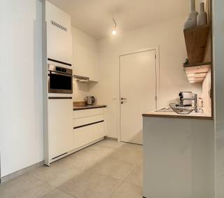 <br />Comfortabel wonen op de eerste verdieping van dit prestigieuze woonproject doe je gegarandeerd in dit appartement. Het heeft een oppervlakte van 68m² en een overdekt, zuidelijk georiënteerd terras van net geen 10m². Een topligging, want je kijkt uit op de Lombaardstraat waar veel fijne winkels liggen en je heel wat passage ziet voorbijkomen. Bovendien heeft het terras een berging, die netjes is weggewerkt in de houten wand. Tot slot zijn er ook enkele geperforeerde luiken die je open en dicht kan schuiven voor zonwering en privacy. <br /><br />Een extra troef is dat er zowel een schuifraam aan de leefruimte als aan de slaapkamer is voorzien. Die kan je tegelijk openschuiven, waardoor het appartement doorloopt in het terras. De badkamer is gelegen aan de slaapkamer en is betegeld met een licht beige vloertegel, net zoals de rest van het appartement. De keuken is wit afgewerkt met licht houten accenten. De liefhebbers kunnen bij honger (overdekt) doorlopen naar de brasserie van het Ursulinenhof. Top!<br /><br />Dit appartement is ook uiterst geschikt als opbrengsteigendom met een mooi maandelijks huurrendement.<br /> 