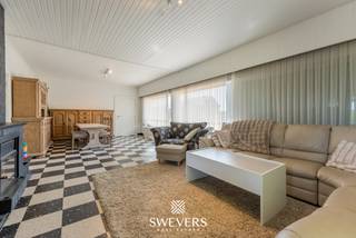 Voor meer info en foto’s, surf naar www.swevers.be – In Halen, aan Kauwplasstraat 55, vind je deze instapklare woning met veel ruimte, licht en een aangename groene omgeving. De woning werd gebouwd in 1963, is verzorgd onderhouden en biedt een bewoonbare oppervlakte van 221 m² op een perceel van 12a 51ca. Op het gelijkvloers geniet je van een ruime leefruimte van 40 m² met zithoek en eethoek. Dankzij de grote raampartijen voelt deze ruimte open en licht aan. De praktische keuken van 16 m² sluit mooi aan op het dagelijkse wooncomfort, terwijl de veranda extra leefruimte biedt met zicht op de tuin. Verder zijn er op deze verdieping drie slaapkamers van 20 m², 16 m² en 13 m², samen met de badkamer. De eerste verdieping telt nog twee bijkomende slaapkamers van elk 12 m². Deze kamers zijn ideaal als kinderkamer, logeerkamer, hobbyruimte of bureau. De woning beschikt daarnaast over een ruime kelder van 68 m² wat tal van opbergmogelijkheden biedt. Daarnaast zijn er twee bijgebouwen aanwezig, namelijk een tuinhuis en een garage, elk met een oppervlakte van ongeveer 21 m². De noordoostelijk georiënteerde tuin biedt een groen en agrarich uitzicht zonder directe bebouwing aan beide zijden en vormt een rustige plek om buiten te genieten. Ook de ligging is praktisch: winkels en een bushalte bevinden zich op 800 meter, scholen op 3 km en de snelweg op 3,6 km. Met vijf slaapkamers, veel bergruimte, een ruime garage en een aangename tuin is dit een comfortabele gezinswoning met tal van mogelijkheden. De woning beschikt over een EPC-label C, waardoor er geen renovatieplicht van toepassing is. Daarnaast zijn er 15 zonnepanelen aanwezig, wat bijdraagt tot de energiezuinigheid van de woning. Ook de elektriciteit werd volledig vernieuwd en zal nog door de eigenaars worden gekeurd. Voor meer informatie, bel 012 699 900. Bron bewoonbare oppervlakte: EPC – verslag. De vermelde oppervlaktes zijn louter indicatief. Swevers Real Estate kan niet aansprakelijk worden gesteld voor eventuele onjuistheden in de verstrekte gegevens.