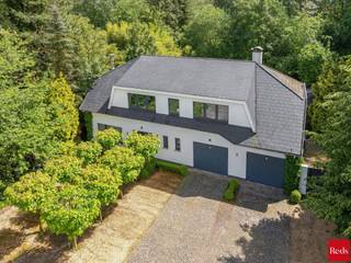 <p>TE KOOP MET PRE-VIEW: enkel op afspraak.</p>
<p>Tussen het groen, op een perceel dat naadloos overgaat in uw eigen stukje natuur met privébos, vindt u deze bijzonder degelijke en stijlvolle villa. Een verwarmd zwembad, een vijver, een petanquebaan en verschillende zit- en ontspanningshoeken zorgen hier elke dag voor een instant vakantiegevoel, gewoon bij u thuis.</p>
<p>INDELING:</p>
<p>Via de verzorgde inkomhal met gastentoilet en vestiairekasten komt u in de ruime leefruimte, volledig afgewerkt met een mooie, brede parketvloer. De gezellige zithoek en lichtrijke eetkamer lopen vlot over in de volledig geïnstalleerde keuken met Amerikaanse koelkast. Blikvanger is het prachtige Falcon gasfornuis, omringd door kwalitatieve, duurzame materialen die deze keuken zowel stijlvol als bijzonder praktisch maken.</p>
<p>Aansluitend vindt u een eerste, zeer functionele berging met wasplaats. Een tweede berging met ingemaakte kasten, waar ook de zwembadtechnieken werden ondergebracht, geeft rechtstreeks uit op de dubbele inpandige garage.</p>
<p>Op de eerste verdieping zorgt een ruime nachthal op parket voor een aangename circulatie naar de vier volwaardige slaapkamers en twee badkamers. Daarnaast is er een kantoorruimte waaraan 2 kleine bergkamers grenzen.De kamers zijn grotendeels uitgerust met maatwerk kasten, wat voor een uiterst praktische en ordelijke inrichting zorgt.</p>
<p>De eerste badkamer is royaal uitgerust met dubbele lavabo, een ligbad, een dubbele inloopdouche, een toilet en een bidet. De tweede badkamer biedt een inloopdouche, een dubbele lavabo en een toilet.</p>
<p>Via een zoldertrap bereikt u nog een praktische bergzolder. Kortom extra opbergruimte ontbreekt hier duidelijk niet.</p>
<p>Tot slot is er beneden nog een wijnkelder met een kruipruimte.</p>
<p>De tuin is een van de absolute troeven van dit eigendom. Het eerste, zuid gerichte deel van de achtertuin geniet maximale privacy en is doordacht ingedeeld:</p>
<p>- Een ontspanningszone met verwarmd zwembad, een buitendouche en een poolhouse met open haard, ideaal om in alle rust te genieten of gasten te ontvangen.</p>
<p>- Net voor het bos ligt een gezellige petanquebaan, die het permanente vakantiegevoel nog versterkt.</p>
<p>Ook praktisch is er goed nagedacht. De voortuin is zo ingericht dat er voldoende parkeerruimte is voor meerdere wagens. Naast de woning, verscholen achter een grote poort, bevindt zich een handige, afgesloten fietsenberging.</p>
<p>De woning werd door de jaren heen met zorg onderhouden en de ramen, de deuren en de buitengevel zijn in perfecte staat, waardoor het geheel een frisse, tijdloze uitstraling heeft. Overal voelt u de keuze voor degelijke materialen, een doordachte indeling en veel aandacht voor comfort en privacy.</p>
<p>Kortom: een instapklare villa op een unieke, groene locatie, waar wonen en genieten naadloos in elkaar overlopen.<br /><br />BIJZONDERHEDEN: <br />- Gunstige locatie<br />- Omgeven door groen<br />- Zuidgerichte tuin<br />- Verwarmd zwembad<br />- Dubbele garage<br />- Grond van 3.631 m², waarvan 1.173 m² bos <br /><br />Voor meer info of een bezoek ter plaatse kan u vrijblijvend contact opnemen met Lieselotte op 03.227.58.58 of lieselotte@reds.be.</p>