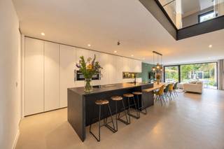<p>In de Mortselstraat in Edegem bevindt zich deze architecturale nieuwbouwwoning uit 2020. De woning onderscheidt zich door haar open karakter, overvloedige natuurlijke lichtinval en verfijnde afwerking. Als BEN-woning (Bijna Energie Neutraal) kies je bij deze woning voor comfort en energiezuinigheid.</p>
<p><strong>INDELING</strong></p>
<p><strong>GELIJKVLOERS<br /></strong>Bij het binnenkomen valt meteen de stijlvolle inkomhal op, afgewerkt met een elegante gietijzeren deur en praktische ingemaakte kasten met geïntegreerd zitbankje. Vanuit de inkomhal heb je toegang tot het gastentoilet en een ruime berging (13 m²) met aansluitingen voor wasmachine en droogkast. De berging biedt bovendien een rechtstreekse doorgang naar de keuken.</p>
<p>De leefruimte vormt het hart van de woning en sluit naadloos aan op de open keuken, die is uitgerust met kwaliteitsvolle toestellen, waaronder een vaatwasser, combi-microgolfoven, stoomoven, inductiekookplaat met geïntegreerde dampkap en een ruime koelkast. Het royale Dekton-werkblad, de verborgen ontbijtkast en de overvloedige kastruimte maken dit tot een bijzonder praktische én stijlvolle leefkeuken.</p>
<p>De leefruimte omvat een groot schuifraam, dat zorgt voor een aangename verbinding met het terras en de zuidgerichte tuin. Het ruime terras van 27 m² is voorzien van een zonneluifel, die op zonnige dagen voor de nodige schaduw zorgt. Ook in de tuin is er voldoende verlichting en zijn er verspreid over de buitenruimte stopcontacten aanwezig, wat extra comfort en gebruiksgemak biedt. Vanuit de tuin geniet je bovendien van een bijzonder zicht op de basiliek van Edegem. Achteraan de tuin bevindt zich een handige servitudeweg. Dankzij de ligging op wandelafstand van het centrum combineert deze woning rustig en comfortabel wonen met winkels, voorzieningen en het dorpsleven binnen handbereik. Een oprit zorgt bovendien voor extra praktisch comfort.</p>
<p>Ook architecturaal weet de woning te verrassen. De open gietijzeren trap en de vide, die zich uitstrekt van de tweede verdieping tot het gelijkvloers, creëren een bijzonder ruimtelijk gevoel en laten het natuurlijke licht tot diep in de woning doordringen. De cementgebonden gietvloer loopt doorheen de volledige woning en zorgt voor een strak, harmonieus geheel.</p>
<p><strong>EERSTE VERDIEPING<br /></strong>Overloop met zicht tot in de nok, gecombineerd met een glazen vloer voor een optimale natuurlijke lichtinval. Drie slaapkamers en een volledig ingerichte badkamer met ligbad, inloopdouche en een ruim badkamermeubel met lavabo.</p>
<p><strong>TWEEDE VERDIEPING<br /></strong>Op de tweede verdieping is er nog een extra slaapkamer, alsook een tweede badkamer die nog naar eigen smaak kan worden afgewerkt.<br /><br /><strong>BIJZONDERHEDEN<br /></strong>Een unieke combinatie van architectuur, comfort, energiezuinigheid en een uitstekende ligging. Ideaal voor wie op zoek is naar een moderne gezinswoning met karakter en oog voor detail.<strong><br /></strong>Vloerverwarming/-koeling d.m.v. een warmtepomp. Ventilatiesysteem D en aluminium schrijnwerk met dubbele beglazing.<br />Regenwaterpomp voor regenwaterrecuperatie voor wc's en wasmachine.<br />Uitgebreid alarmsysteem waar ook de rookmelders aan gekoppeld zijn.</p>
<p><span>Meer informatie en attesten: www.immopoint.be</span></p>