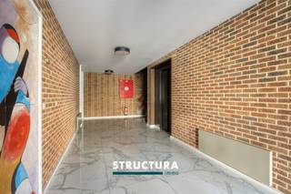 Dit ruime appartement van ca. 134 m² bevindt zich op de bovenste verdieping en combineert een kwalitatieve afwerking met bijzonder veel lichtinval dankzij de grote raampartijen. De ligging is praktisch, met winkels, openbaar vervoer, het UZ en de Ring in de nabije omgeving. Met onder meer 20 privatieve zonnepanelen, airconditioning, een conform gekeurde elektrische installatie en EPC-label B is het appartement bovendien goed uitgerust.IndelingDerde verdieping: inkomhal die overgaat in een ruime centrale hal, waar voldoende plaats is voor bijvoorbeeld een bureau of extra werkruimte met aansluitend de leefruimte met open en volledig ingerichte keuken, die luxueus en met kwalitatieve materialen werd afgewerkt. Verder zijn er twee ruime slaapkamers, een badkamer met dubbele lavabo en douche, met eveneens plaats voor een wasmachine en droogkast. Daarnaast beschikt het appartement over een apart toilet en een praktische berging.Ondergronds: Parkeerplaats met laadpaal verplicht bij aan te kopen aan € 30.000Karakteristieken- Ca. 134 m² bewoonbare oppervlakte- Grote raampartijen en veel natuurlijke lichtinval- 2 ruime slaapkamers- Luxueus uitgewerkte open keuken- Kwalitatieve afwerking- Airconditioning- 20 privatieve zonnepanelen- EPC B- Elektrische installatie conformEen ruim en verzorgd appartement met veel lichtinval, een sterke energieprestatie en een vlot bereikbare ligging. Interesse? Neem contact met ons op voor meer informatie of een bezoek ter plaatse via 02 460 80 46 of info@structura.be