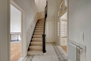 <p>De statige gevel aan de Jan Van Rijswijcklaan trekt al meer dan een eeuw de aandacht. Deze eclectische burgerwoning, ontworpen door architect <strong>Hendrik Delvaux</strong>, ademt nog steeds dezelfde grandeur als toen ze gebouwd werd. Een gevel waar je automatisch even naar opkijkt. En eenmaal de authentieke voordeur opengaat, besef je al snel dat de buitenkant nog maar het begin was.</p>
<p>Welkom.<br />De inkomhal is zonder overdrijven indrukwekkend. Authentieke mozaïekvloeren, kleurrijke glas-in-loodramen, sierlijke moulures die tot aan het plafond doorlopen...<br />Links wacht een royale bureauruimte. Ideaal voor wie regelmatig thuiswerkt, klanten ontvangt of droomt van een stijlvolle bibliotheek.</p>
<p>Verder opent de woning zich langzaam.<br />De eetkamer vormt de verbinding tussen oud en nieuw. Achteraan ligt de volledig uitgeruste leefkeuken. Strak vormgegeven, afgewerkt met luxueuze materialen en voorzien van een praktische keukenberging.<br />En terwijl je staat te koken, kijk je uit op een stijlvolle stadstuin.<br />Waar je rustig ontbijt, lang aperitieft of even aan de stad ontsnapt.</p>
<p>Via de elegante trap gaan we naar de eerste verdieping.<br />De royale leefruimte strekt zich uit aan de achterzijde van de woning. Grote ramen zorgen voor een zee van licht en via het aansluitend, ruime terras verhuis je op zonnige dagen moeiteloos naar buiten.<br />Aan de straatzijde bevindt zich nog een tweede grote kamer. Vandaag misschien een bureau, morgen een tv-kamer, speelkamer of extra slaapkamer.</p>
<p>Nog een verdieping hoger wacht de privésuite.<br />De master bedroom ademt rust en ruimte. Aansluitend vind je een royale dressing en een luxueuze badkamer waar natuursteen, verfijnde materialen en een tijdloze afwerking perfect samenkomen. Met zowel een ligbad als een ruime inloopdouche voelt elke ochtend hier een klein beetje als een hotelverblijf.<br />Ook de praktische wasruimte kreeg een volwaardige plaats op deze verdieping.<br />Helemaal boven bevinden zich nog drie slaapkamers en een tweede badkamer.</p>
<p>Achter al die authentieke charme schuilt bovendien een woning die volledig, kwalitatief werd gerenoveerd.<br />Met een EPC B, conforme elektriciteit, een asbestveilig attest en een hoogwaardige totaalrenovatie geniet je hier volop van karakter, maar ook van jarenlang zorgeloos wooncomfort.</p>
<p>Troeven<br />- Prachtig volledig gerenoveerde burgerwoning<br />- Statige gevel <br />- Royale bewoonbare opp. 353 m²<br />- EPC B<br />- AREI conforme<br />- Asbestveilig<br />- Authentieke elementen met oog voor detail<br />- Indrukwekkende inkomhal<br />- Hoge plafonds en prachtige parketvloeren<br />- Twee ruime bureauruimtes / multifunctionele kamers<br />- Stadstuin en terras op de eerste verdieping<br />- Grote droge kelder</p>